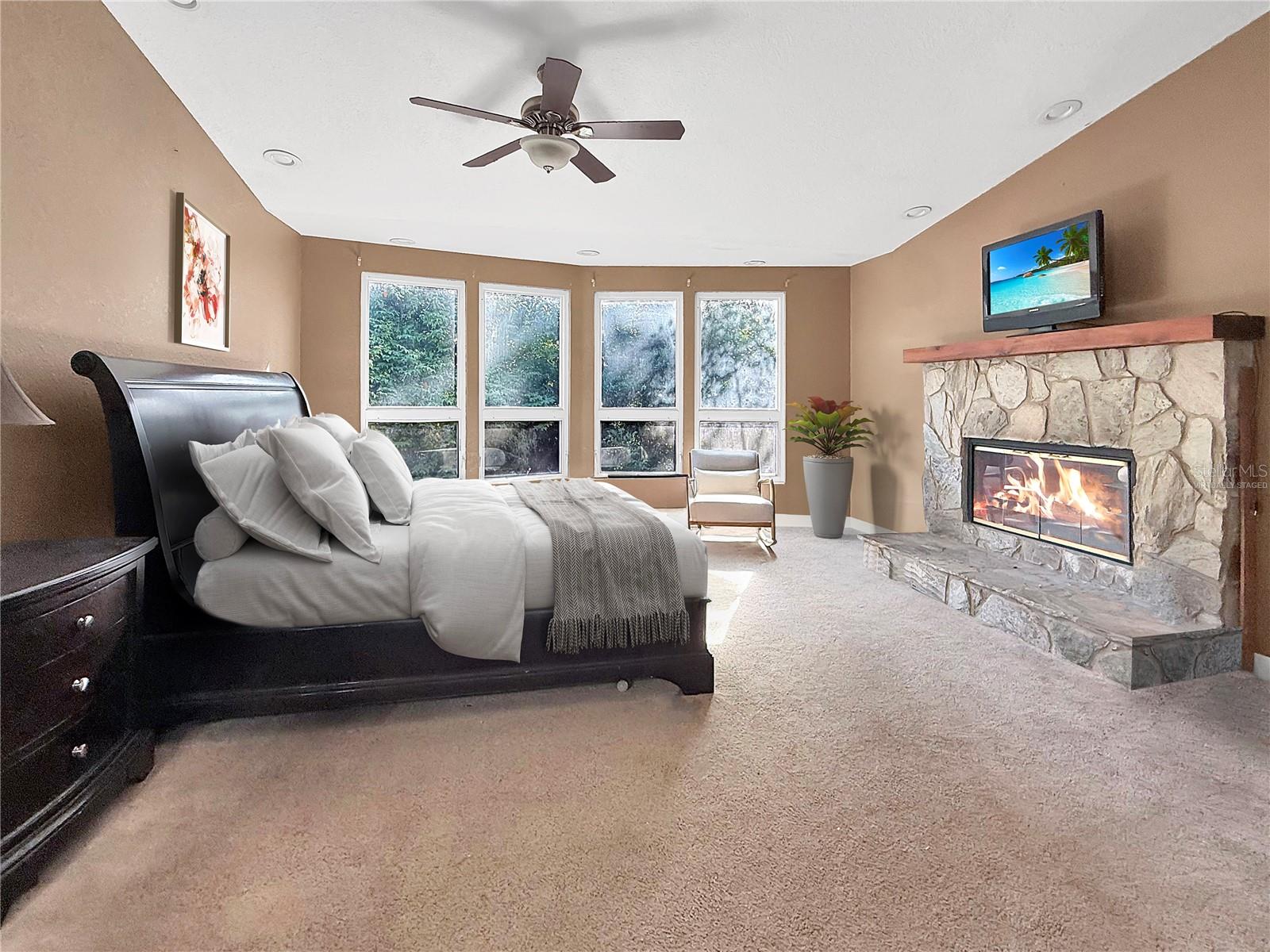 Beautiful stone wood burning fireplace in the primary suite-virtually staged