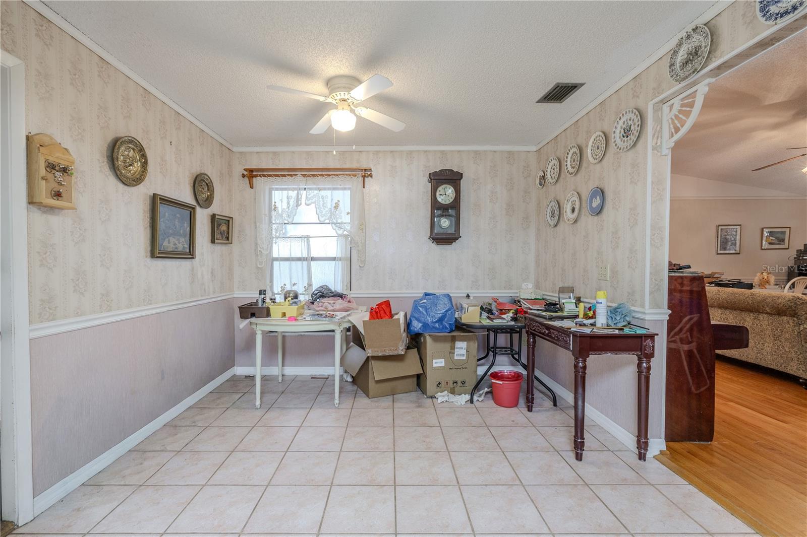 Eat-in kitchen nook with tile flooring, chair rail detailing, a ceiling fan light, and a sunlit window, offering flexible space for casual dining or a breakfast table.