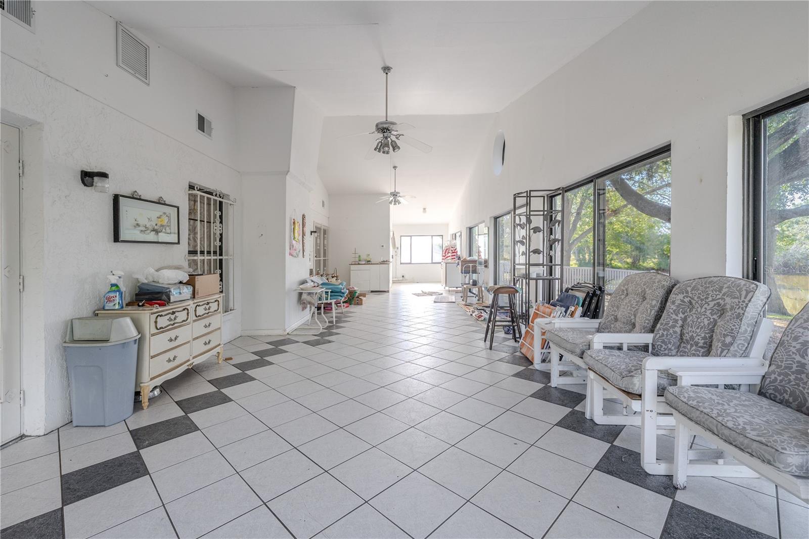 Expansive, air-conditioned fully enclosed 50.11 X 14.6 ft. Florida room with tile flooring, ceiling fans, and a wall of windows and sliding glass doors overlooking the yard and pond, plus the convenience of a private bathroom.