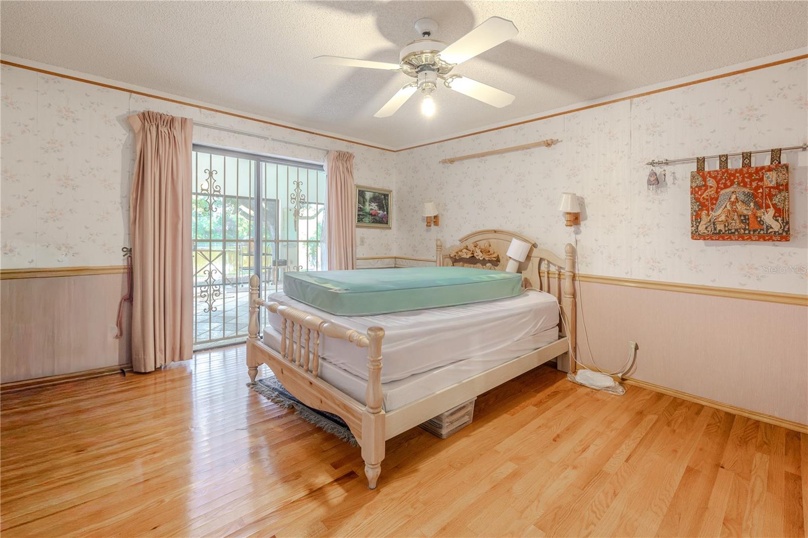 Additional view of primary bedroom with hardwood floors, ceiling fan, ample natural light, and a private en-suite bath.