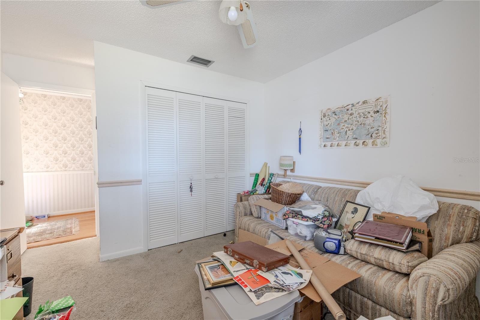 Additional view of the secondary carpeted bedroom with a ceiling fan, chair rail, natural light, and built-in closet.