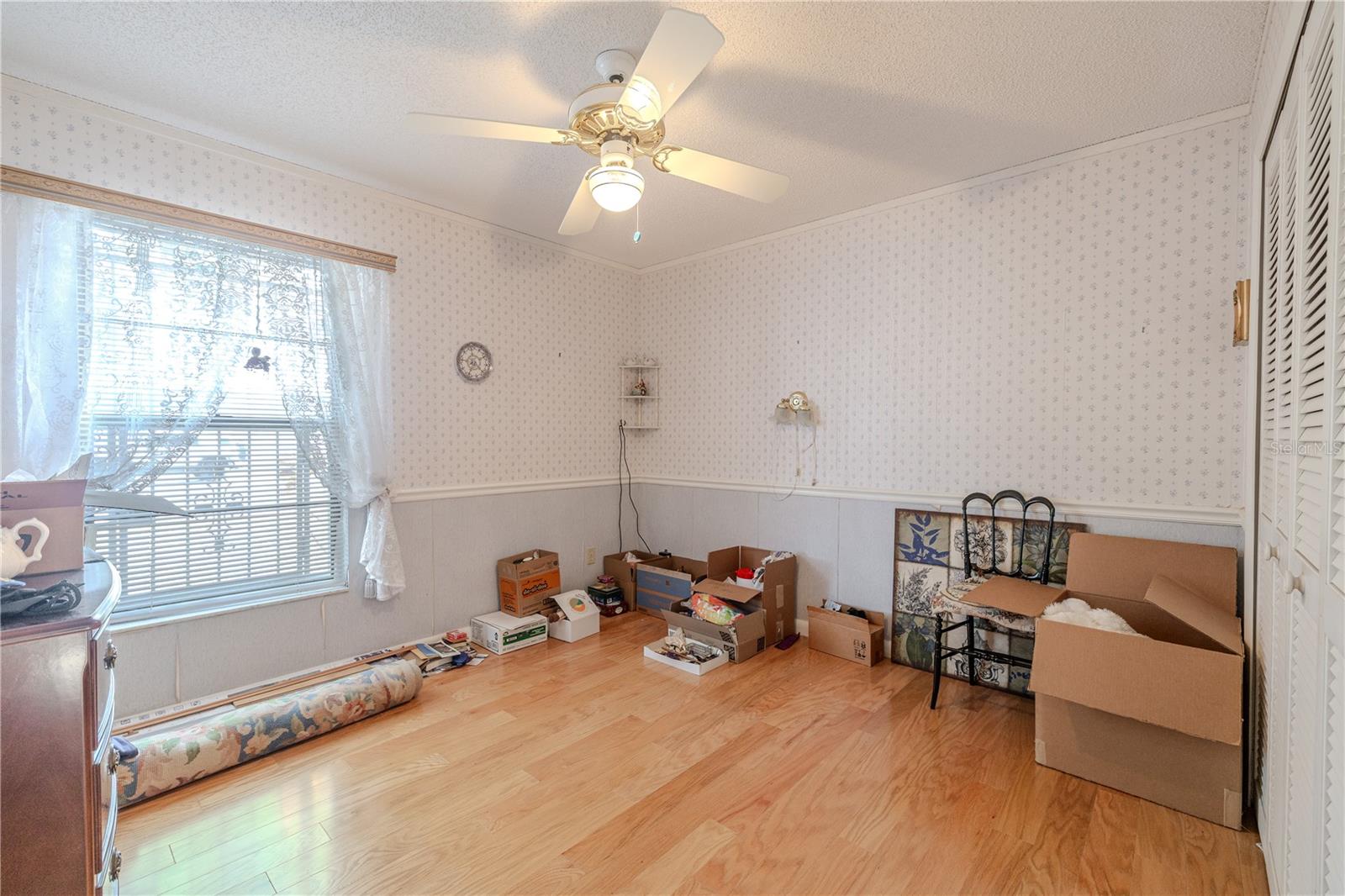 3rd Light-filled 13.7 X 10.7 bedroom with hardwood floors, a ceiling fan, spacious closet doors, and a large window creating a bright, airy feel.