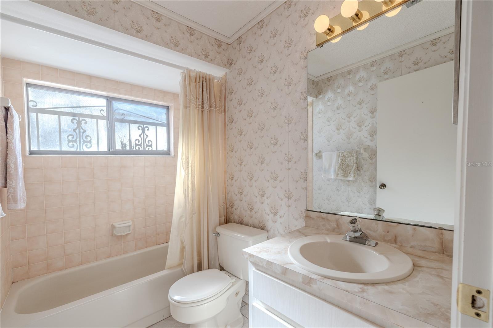 Full 7.4 X 5.3 second bath with a tub/shower combo, tile flooring, oversized privacy window, and a single vanity with ample mirror space.