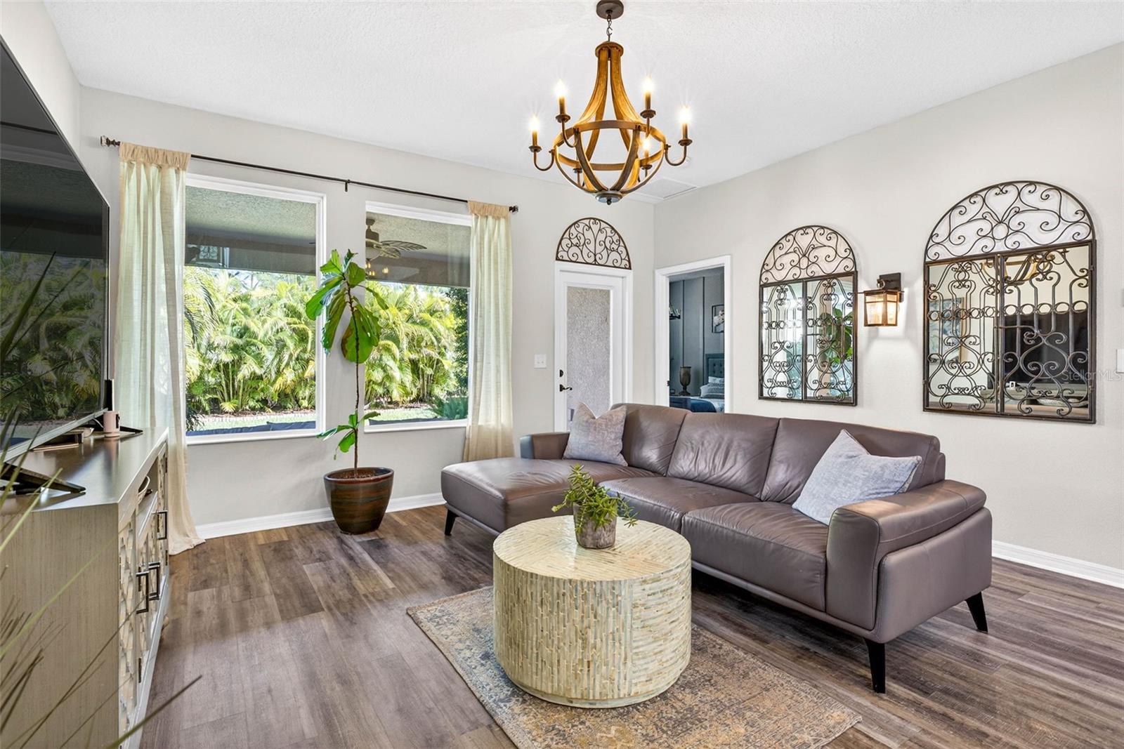 Living area with views of the lanai and tropical oasis in the back. Door leads to lanai and two windows provide plenty of natural light.