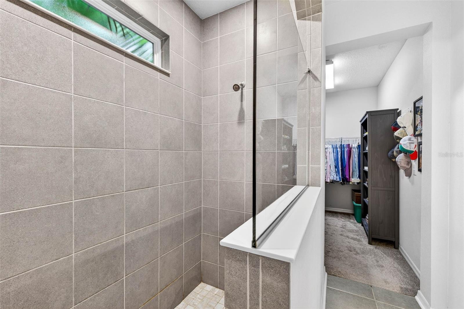 Window in shower provides natural light but is still private. Primary walk in closet is beyond the shower.