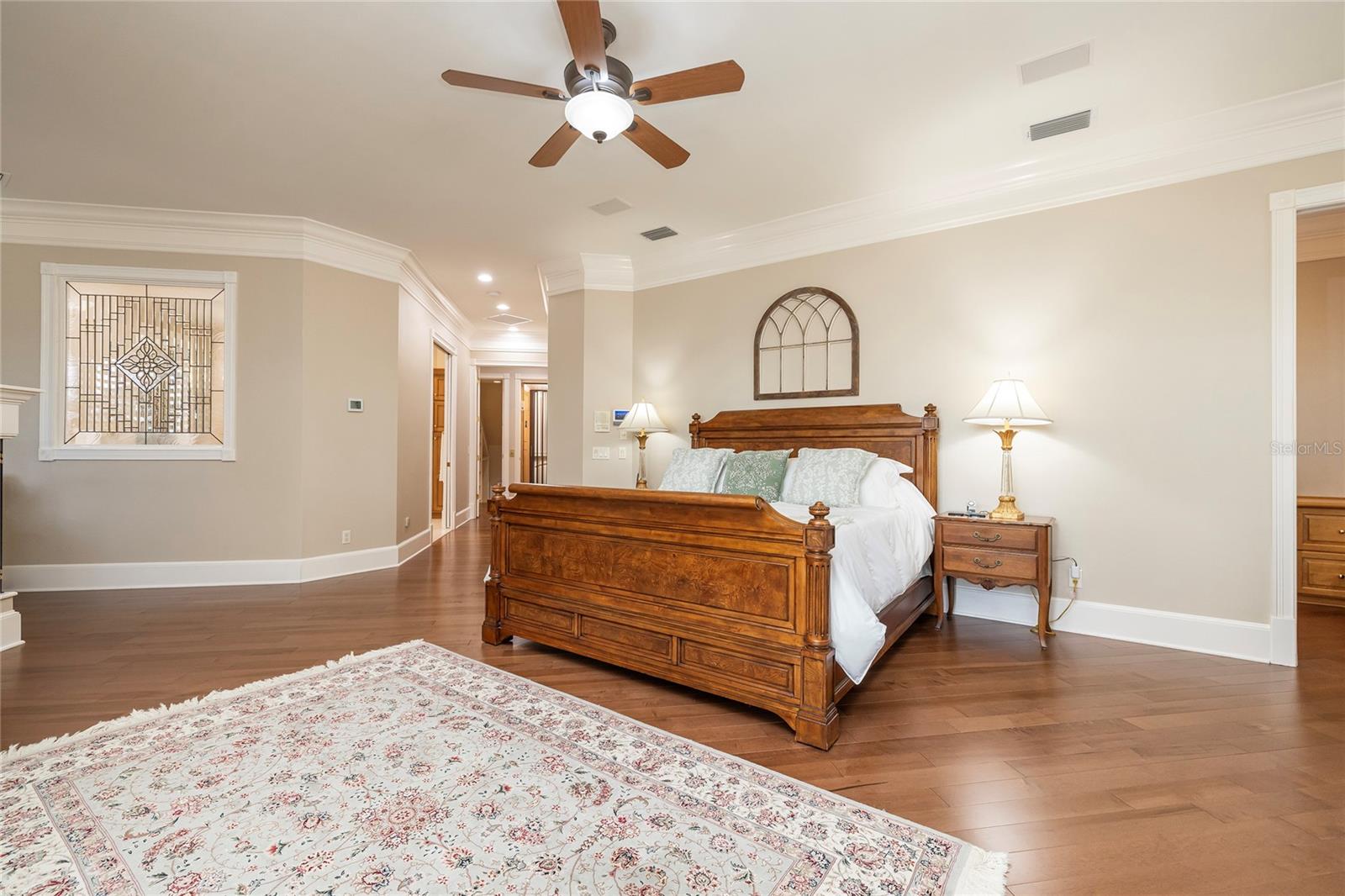 Primary bedroom with two large walk-in closets, a separate built-in office, a sitting area, a grand elegant bath, and a coffee station.
