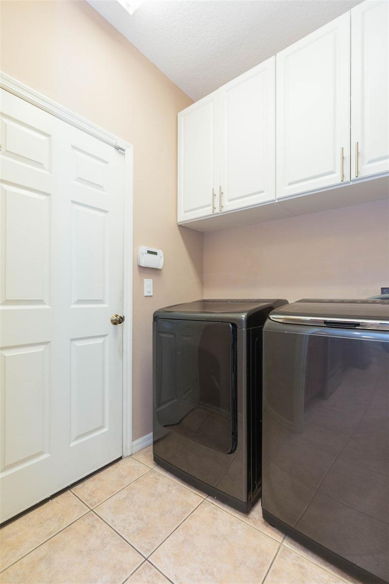 Laundry room adjacent to kitchen with additional storage