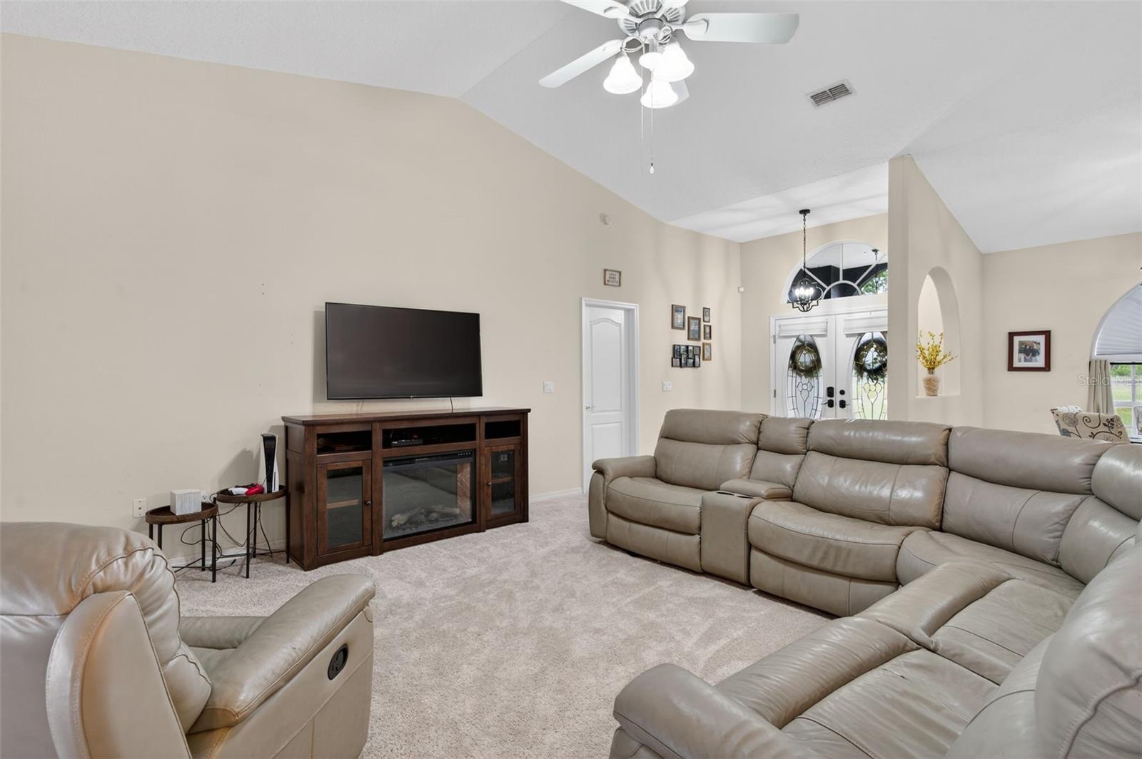 Living Room features vaulted ceilings, Lanai/Pool access, and brand new carpet.