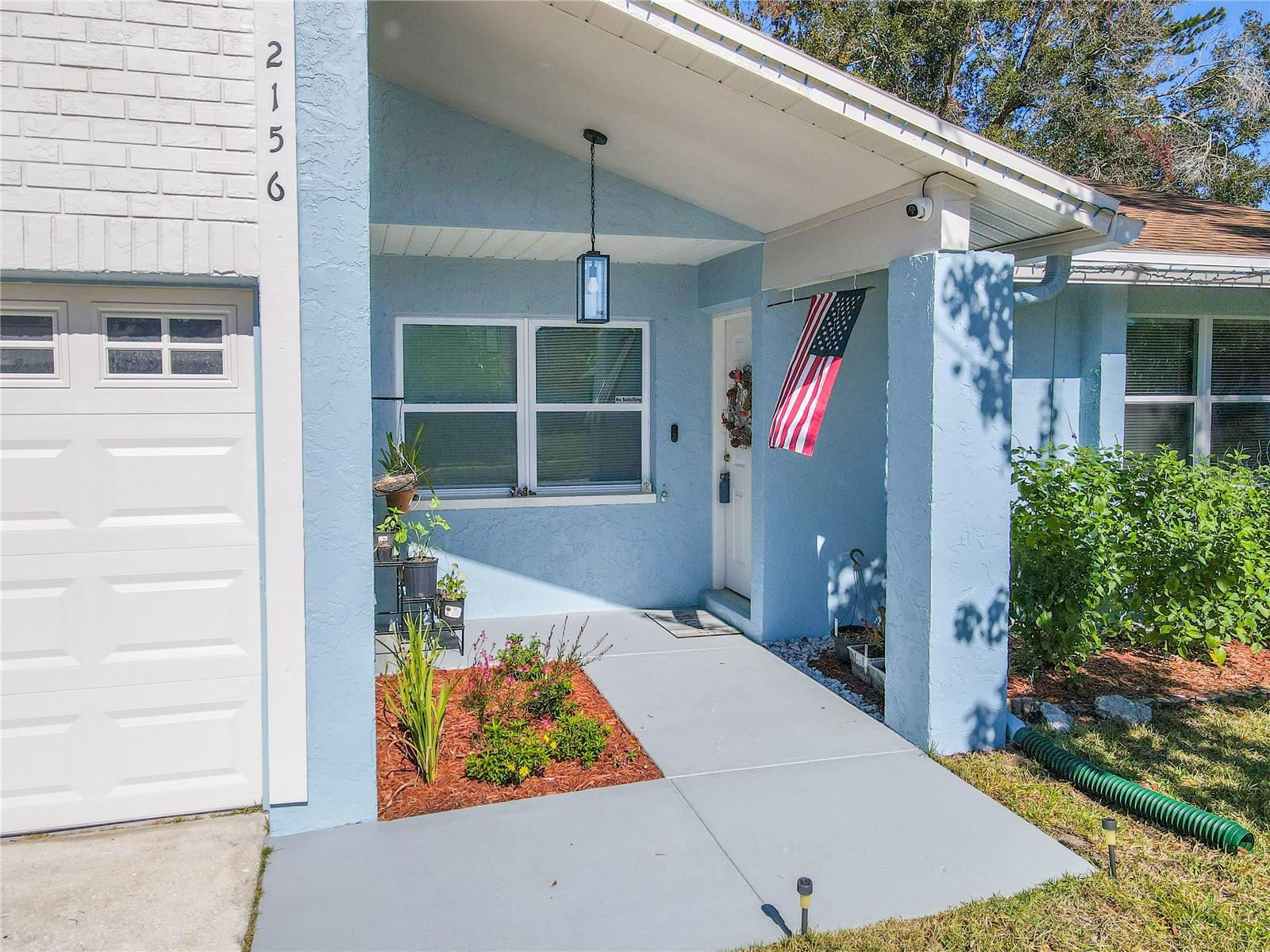 Freshly painted entry walkway leads to the covered front porch, accented by tidy landscaping and an inviting front door with updated exterior appeal.
