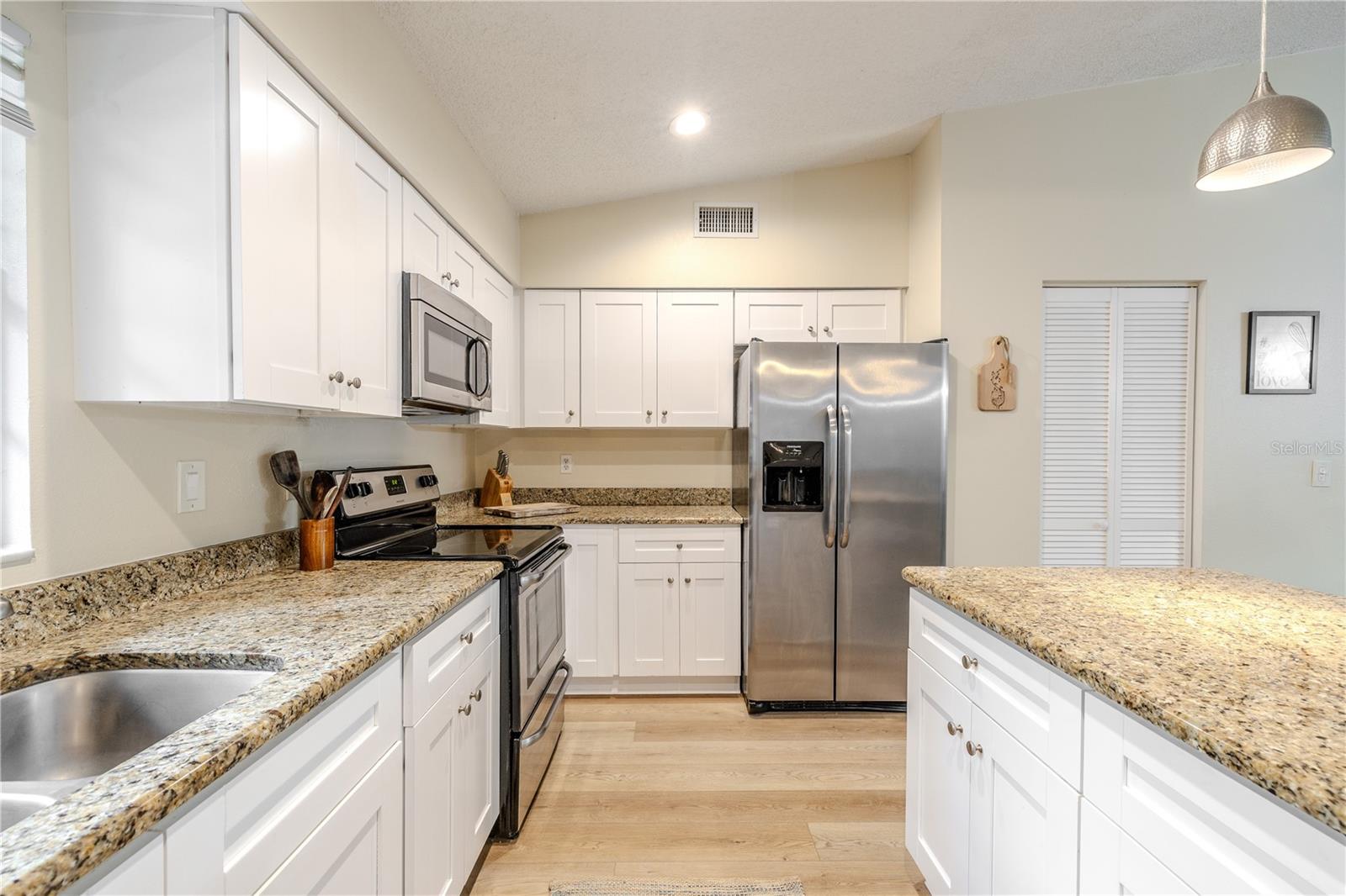 Spacious, upgraded kitchen featuring granite countertops, abundant white cabinetry for storage, pantry closet, stainless appliances, recessed lighting, and a large island that’s perfect for prep, serving, and gathering.