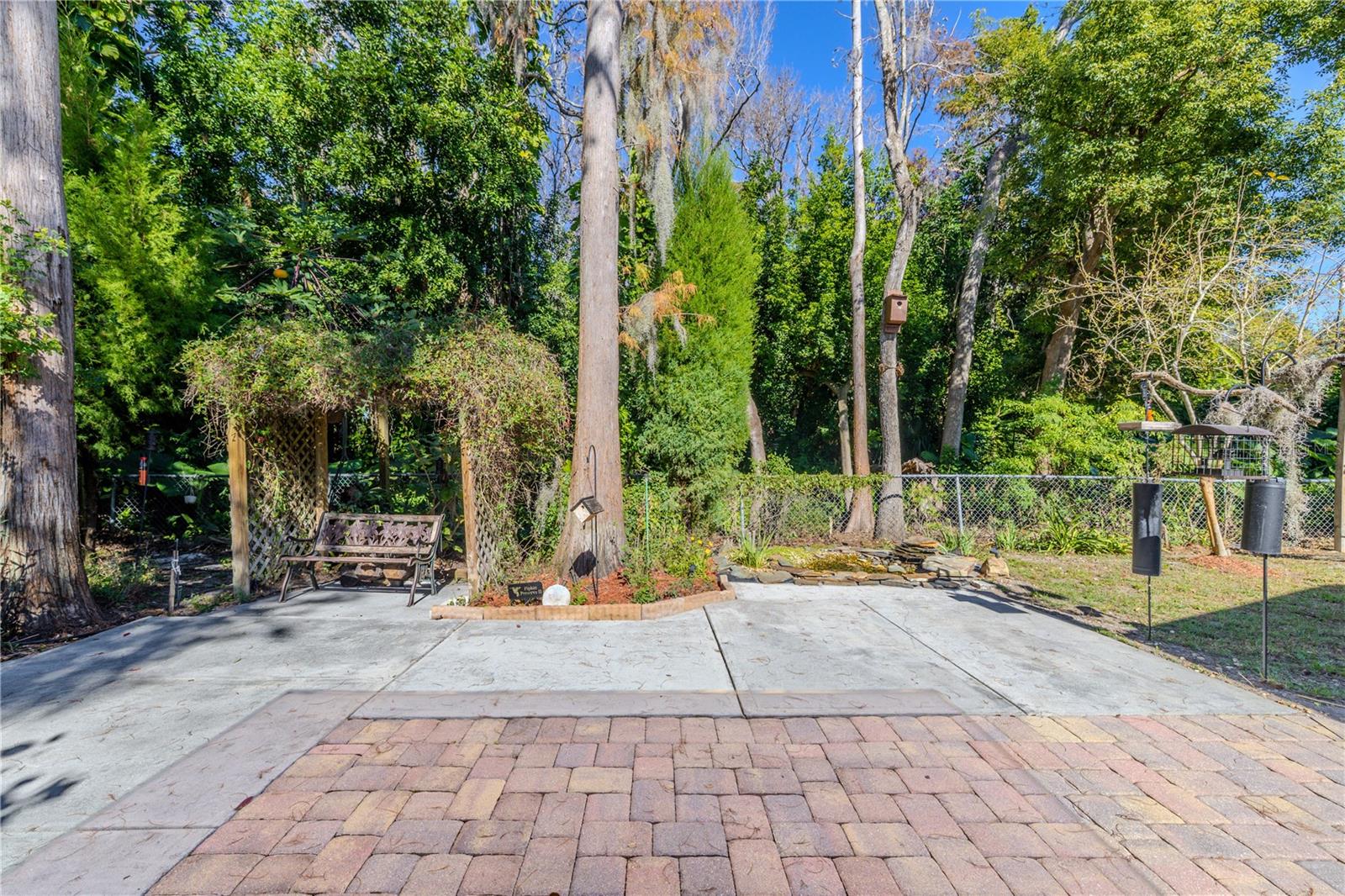 Private backyard retreat featuring a spacious patio, lush tropical landscaping, a charming garden arbor with seating, and tranquil preserve views for ultimate serenity.