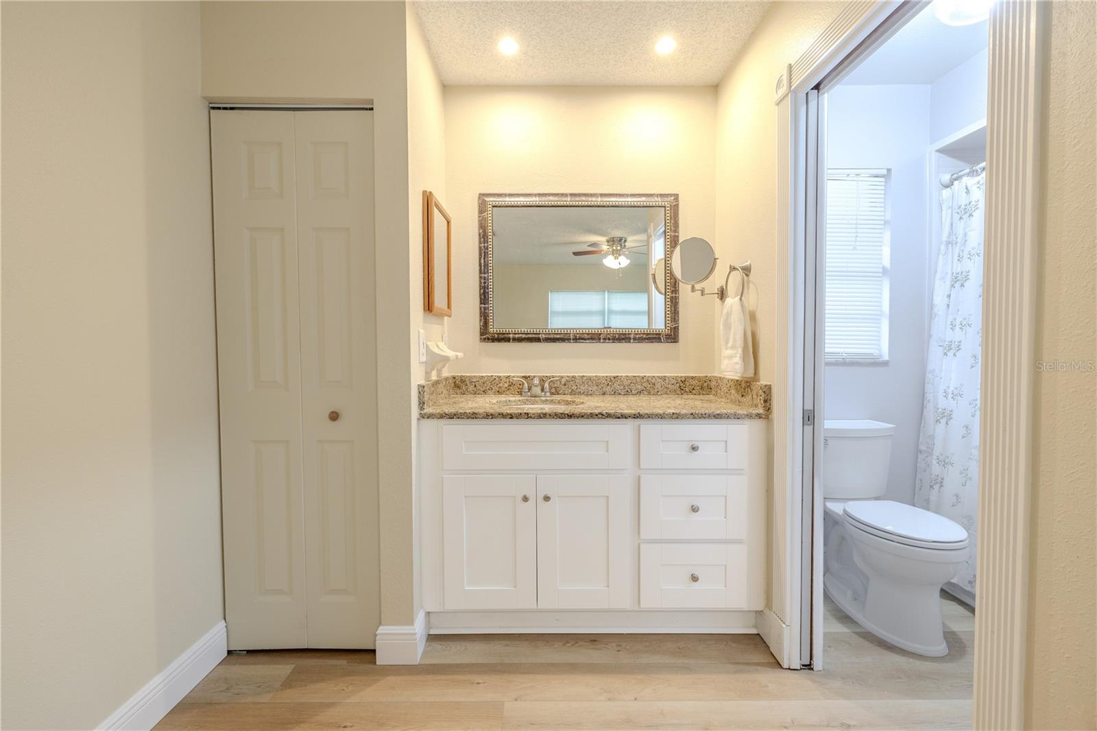Bright vanity area with a granite countertop, linen closet, ample cabinet storage, recessed lighting, and convenient access to the windowwed private bath with framed with wide Craftsman-style casing/trim.