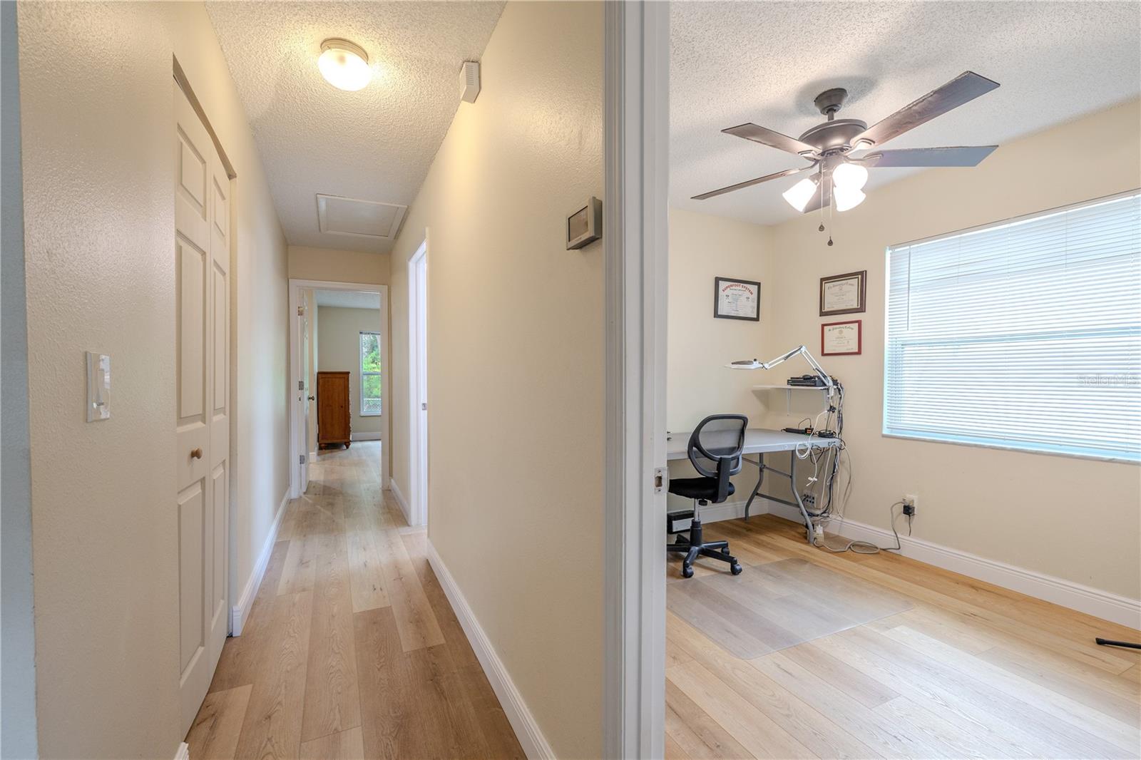 Hallway view showcasing with a glimpse into the third bedroom wing with wide-plank vinyl wood flooring and ample linen closet.