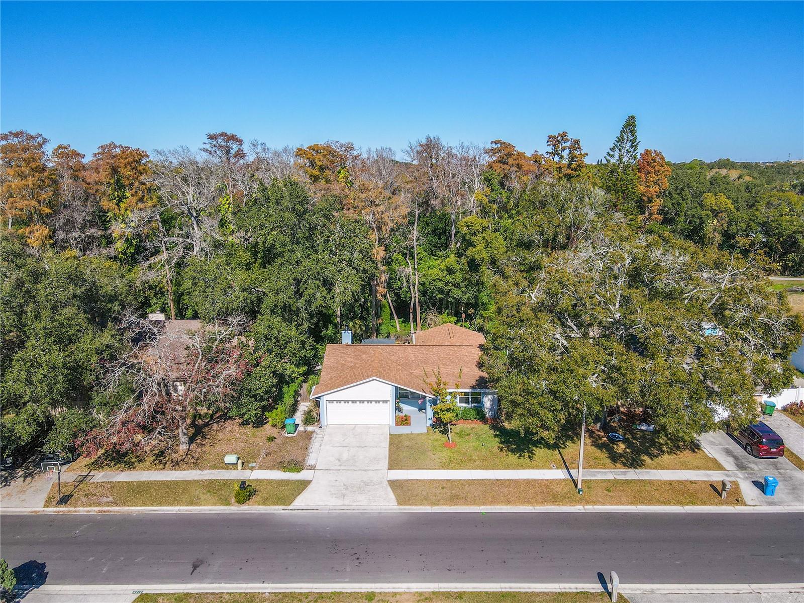 Additional aerial view of this charming 3 bedroom, two full bath single-story home with a spacious two-car garage, wide driveway, and inviting covered entry, featuring a clean, refreshed exterior and neat landscaping, with the added privacy of a lush preserve backdrop behind the home.