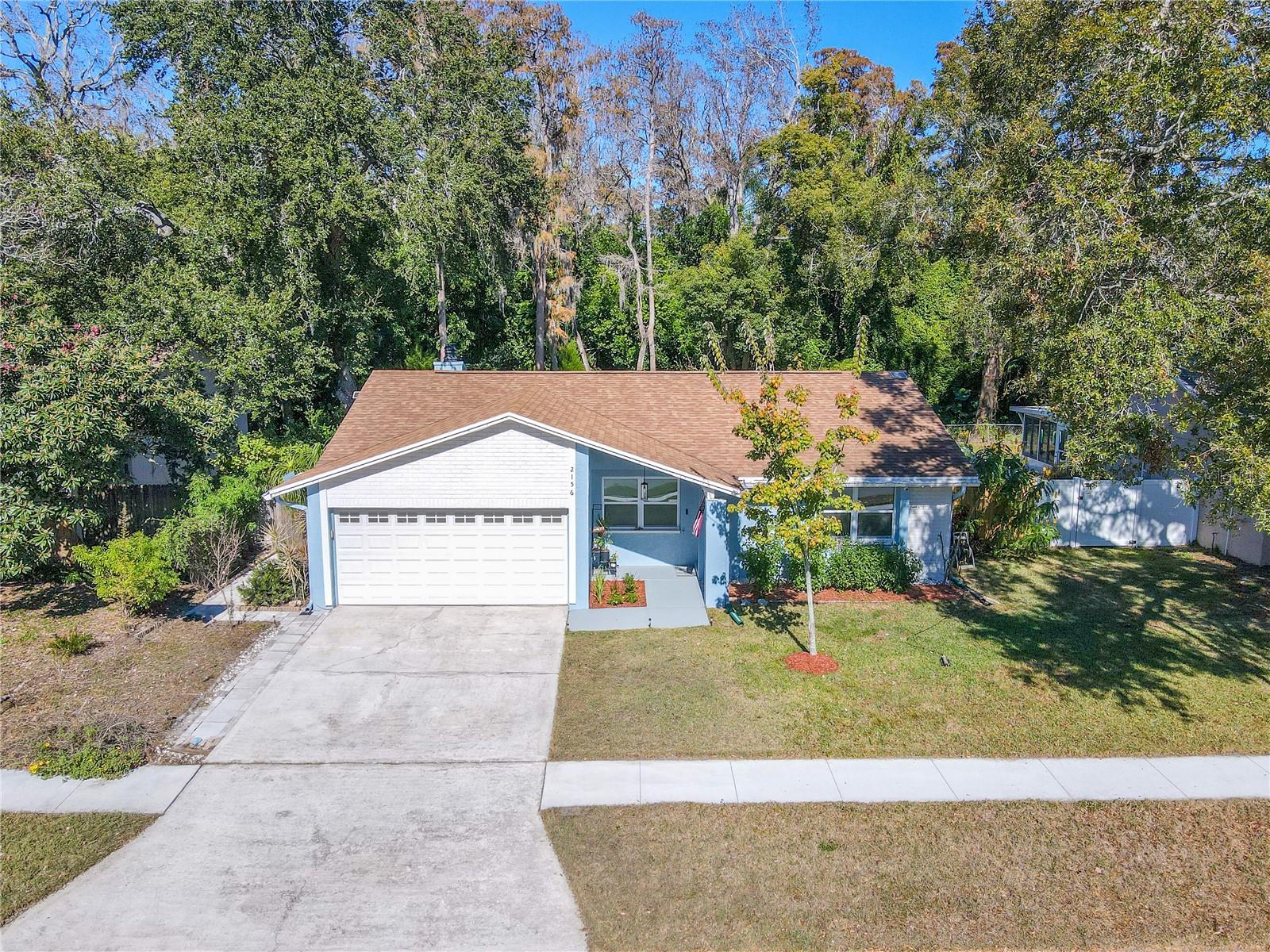 Additional aerial view of this charming 3 bedroom, two full bath single-story home with a spacious two-car garage, wide driveway, and inviting covered entry, featuring a clean, refreshed exterior and neat landscaping, with the added privacy of a lush preserve backdrop behind the home.