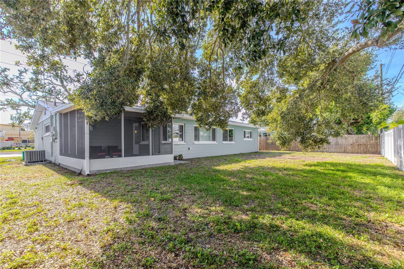 Spacious backyard offers plenty of room to play or entertain, featuring mature shade trees and a screened patio for relaxing Florida outdoor living.