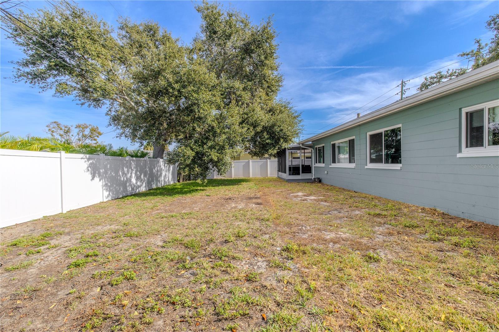 Fenced backyard provides a wide open lawn with mature shade trees and easy access to the screened patio—perfect for play, and outdoor entertaining.