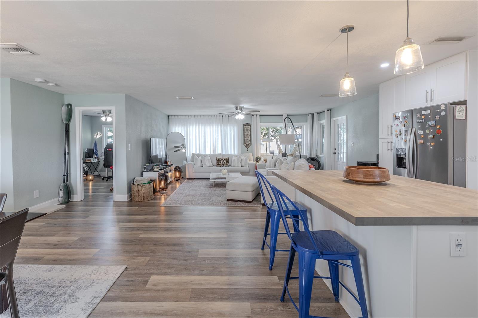 Bright open-concept layout features wide-plank vinyl flooring and a spacious kitchen with a large food grade butcher block breakfast bar that flows seamlessly into the inviting living area.