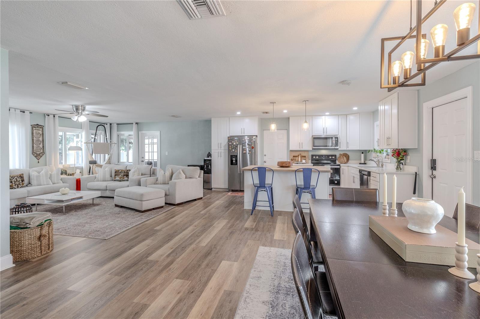 Stunning open-concept layout showcases wide-plank vinyl flooring, a bright living area, and a beautifully modern kitchen with island seating—perfect for entertaining and everyday living.