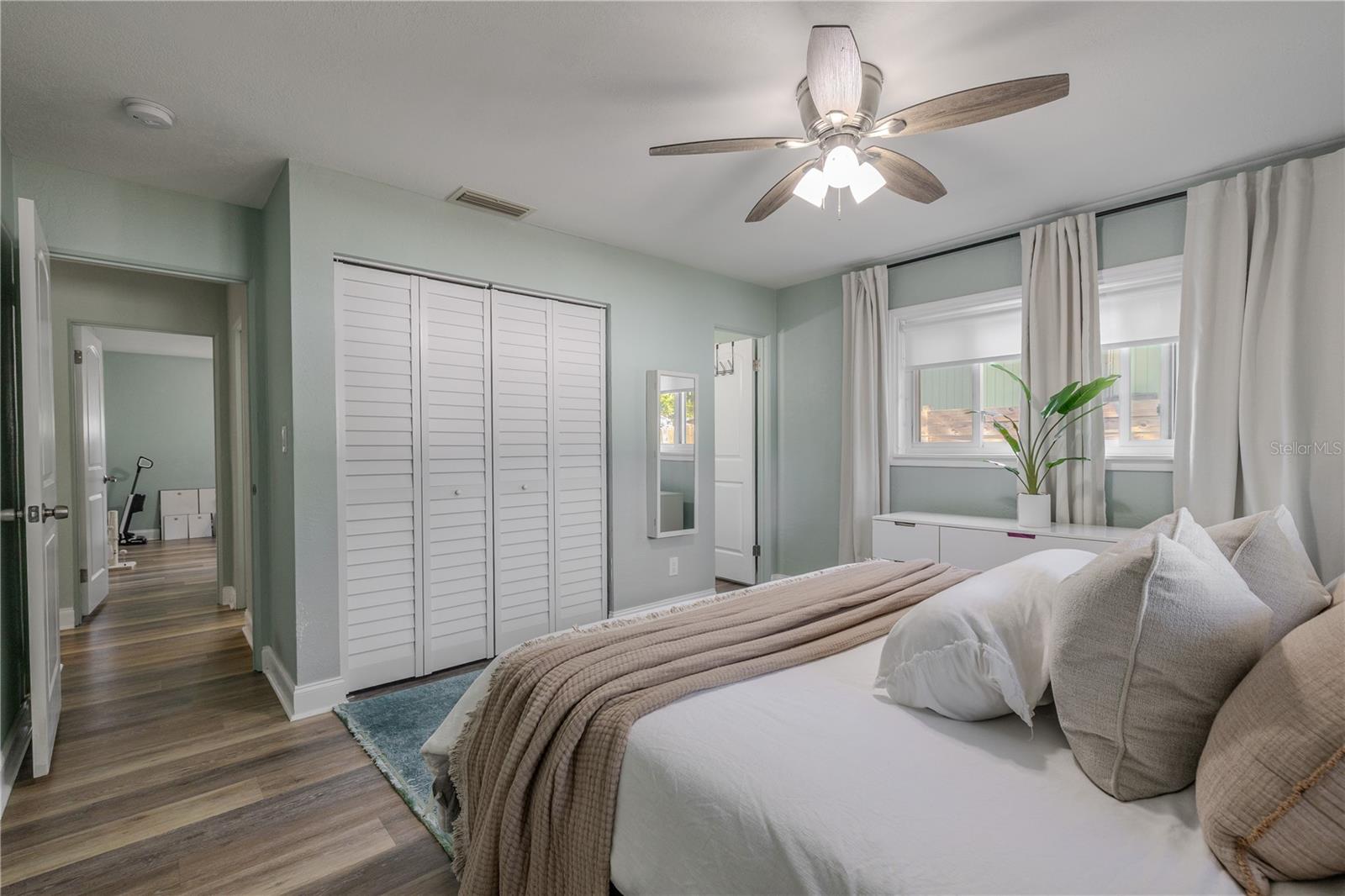Primary bedroom offers a peaceful retreat with wide-plank flooring, a modern ceiling fan, and generous closet space, all filled with soft natural light.
