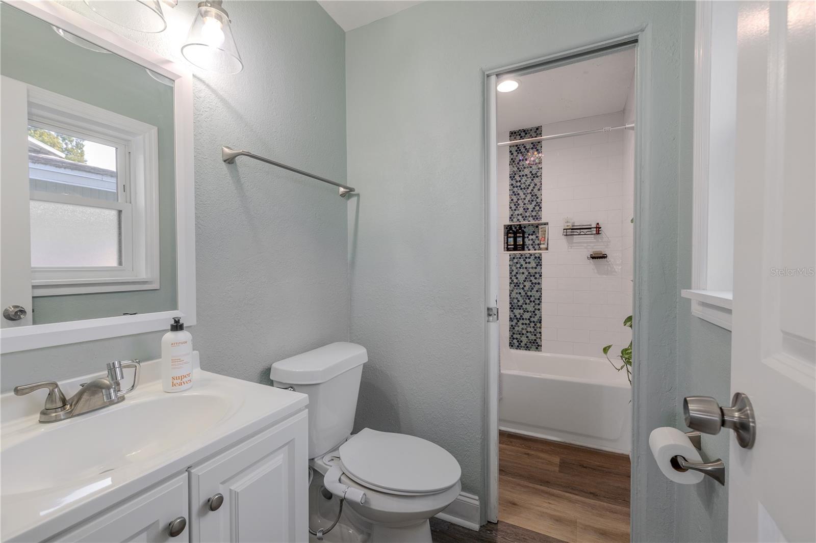 Bright bathroom features a clean vanity with modern lighting and a tub/shower combo accented by stylish tile detail for a fresh, contemporary feel.