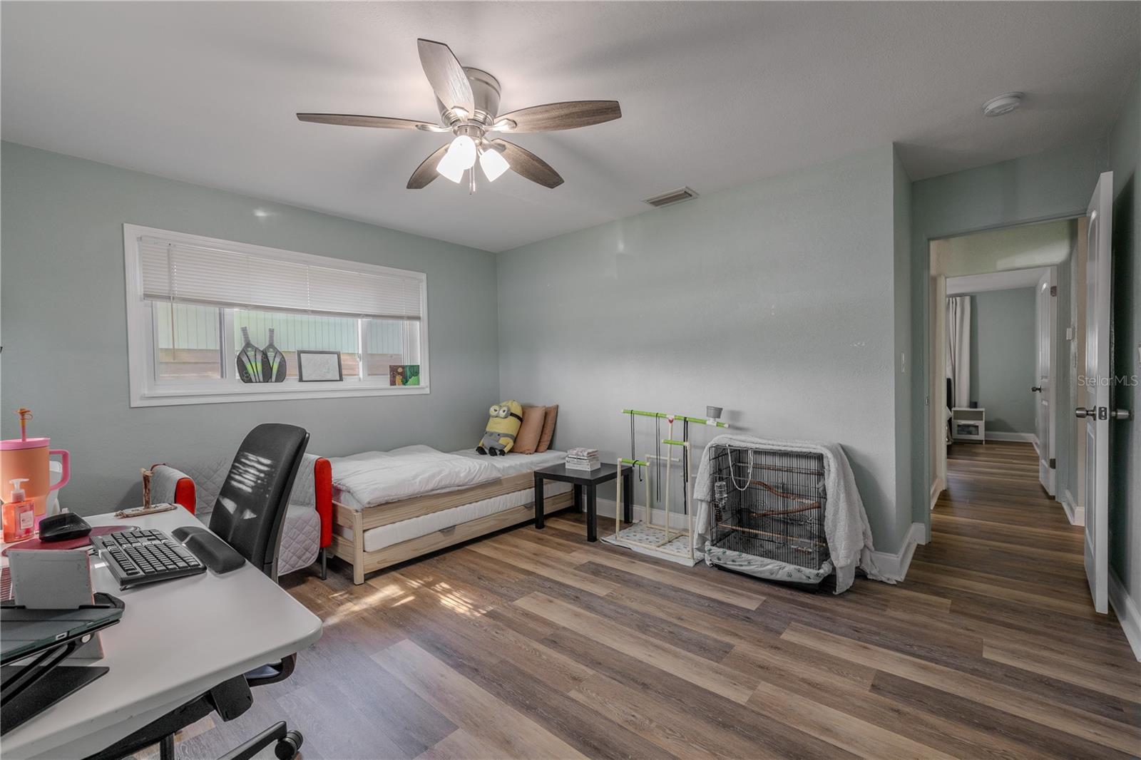 Versatile second bedroom features wide-plank vinyl flooring, a modern ceiling fan, and a bright window—ideal for a home office, guest room, or flex space.