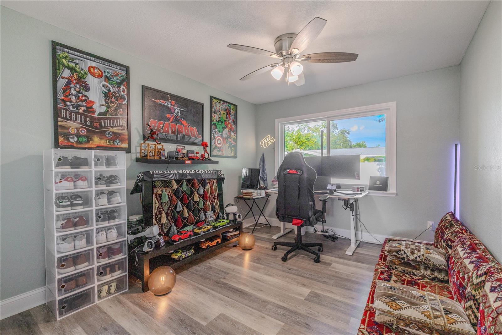 Third bedroom features wide-plank flooring, a modern ceiling fan, and great natural light—ideal for a home office, guest bedroom, or creative studio.