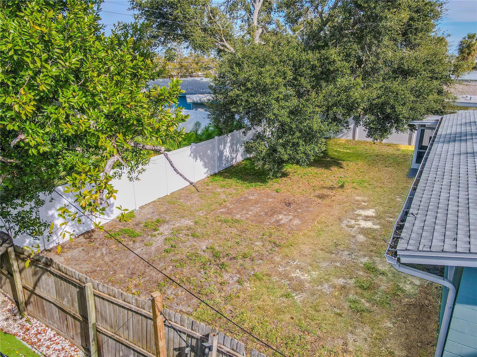 Overhead view highlights the backyard with mature shade trees and plenty of open space—ideal for pets, play, or outdoor entertaining.