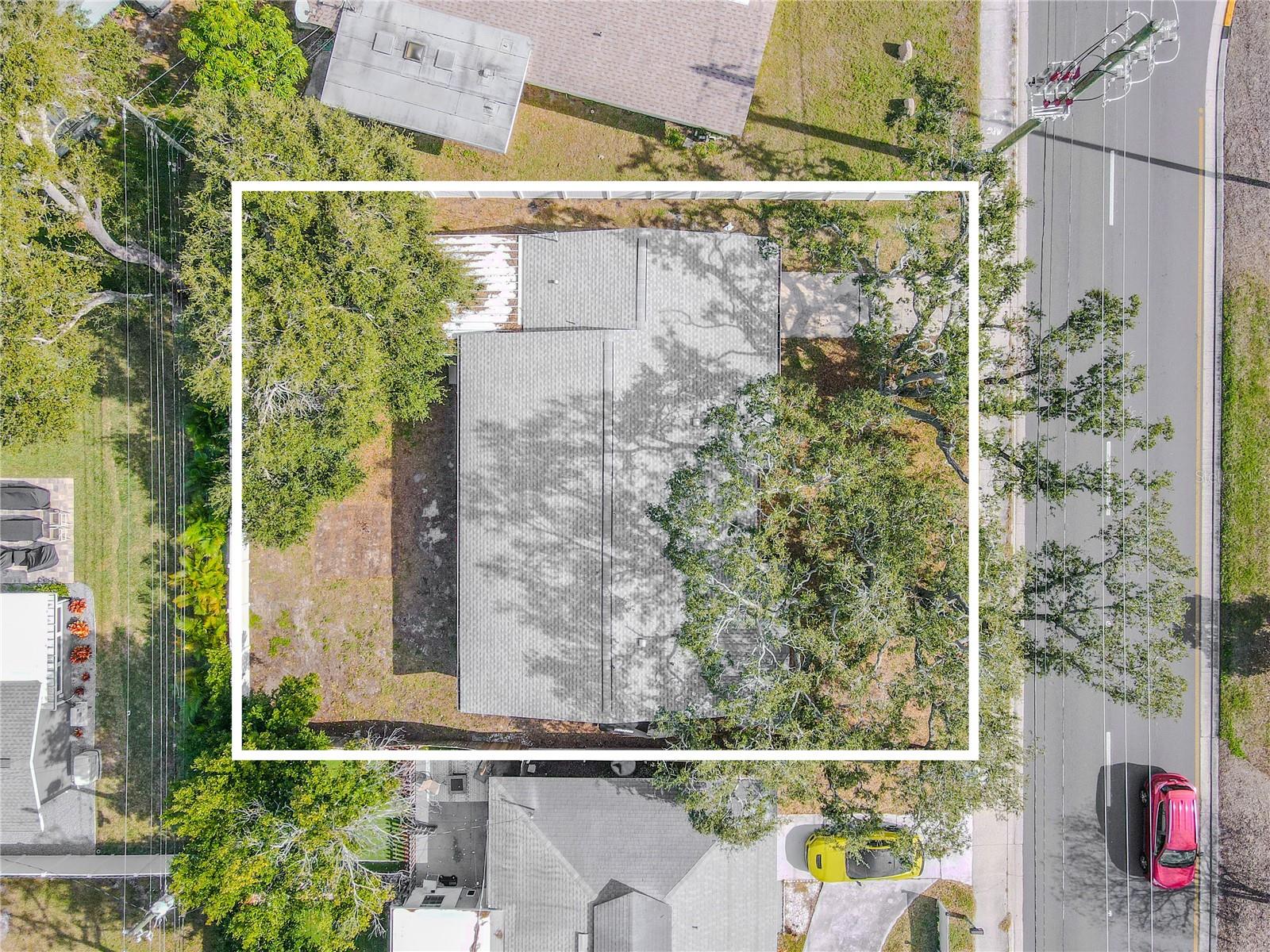Aerial view showcases the home’s expansive lot with mature trees and back yard, offering both privacy and plenty of outdoor space.