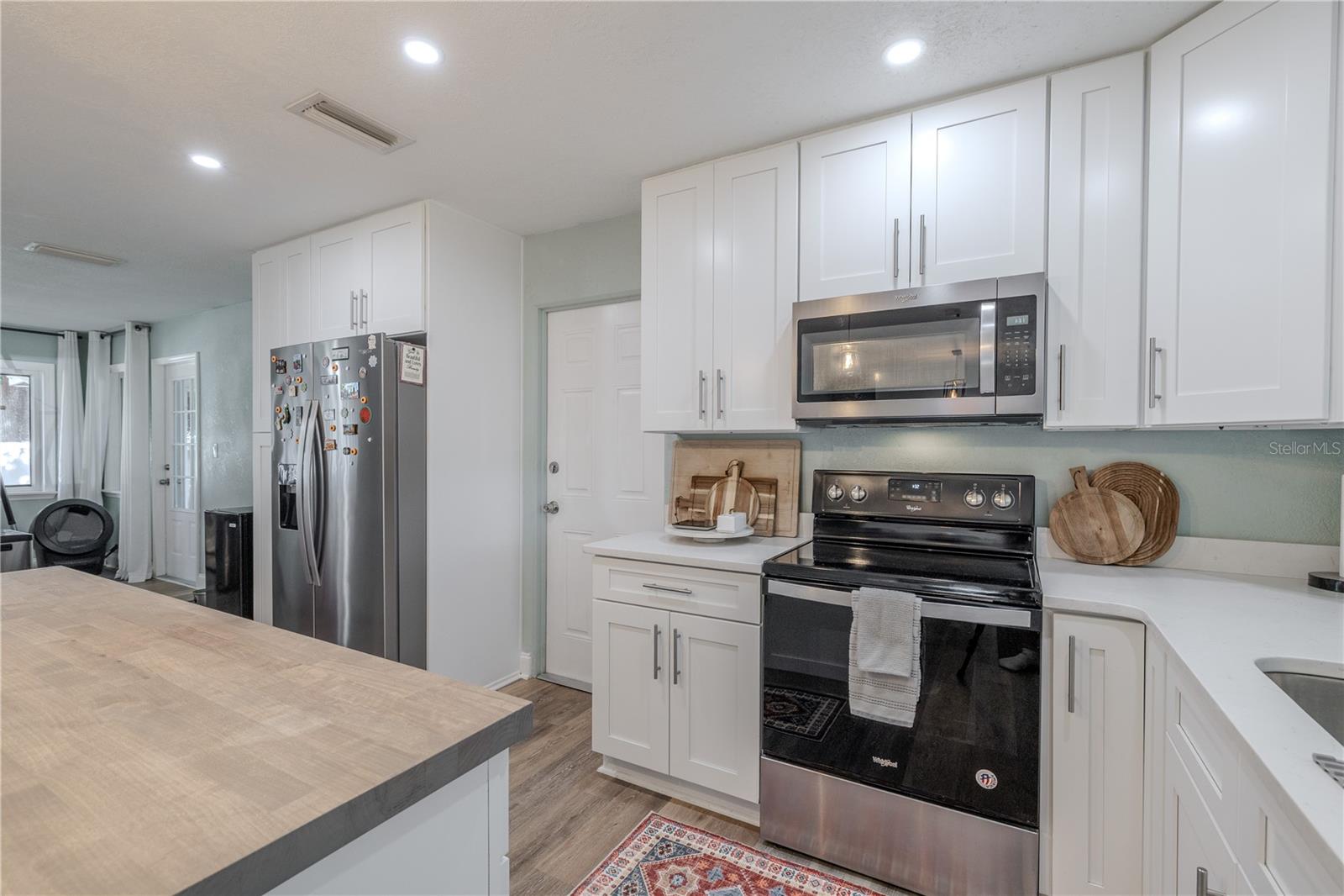 Crisp, modern kitchen features abundant shaker cabinetry, stainless appliances, and bright recessed lighting, with plenty of prep space and storage throughout.