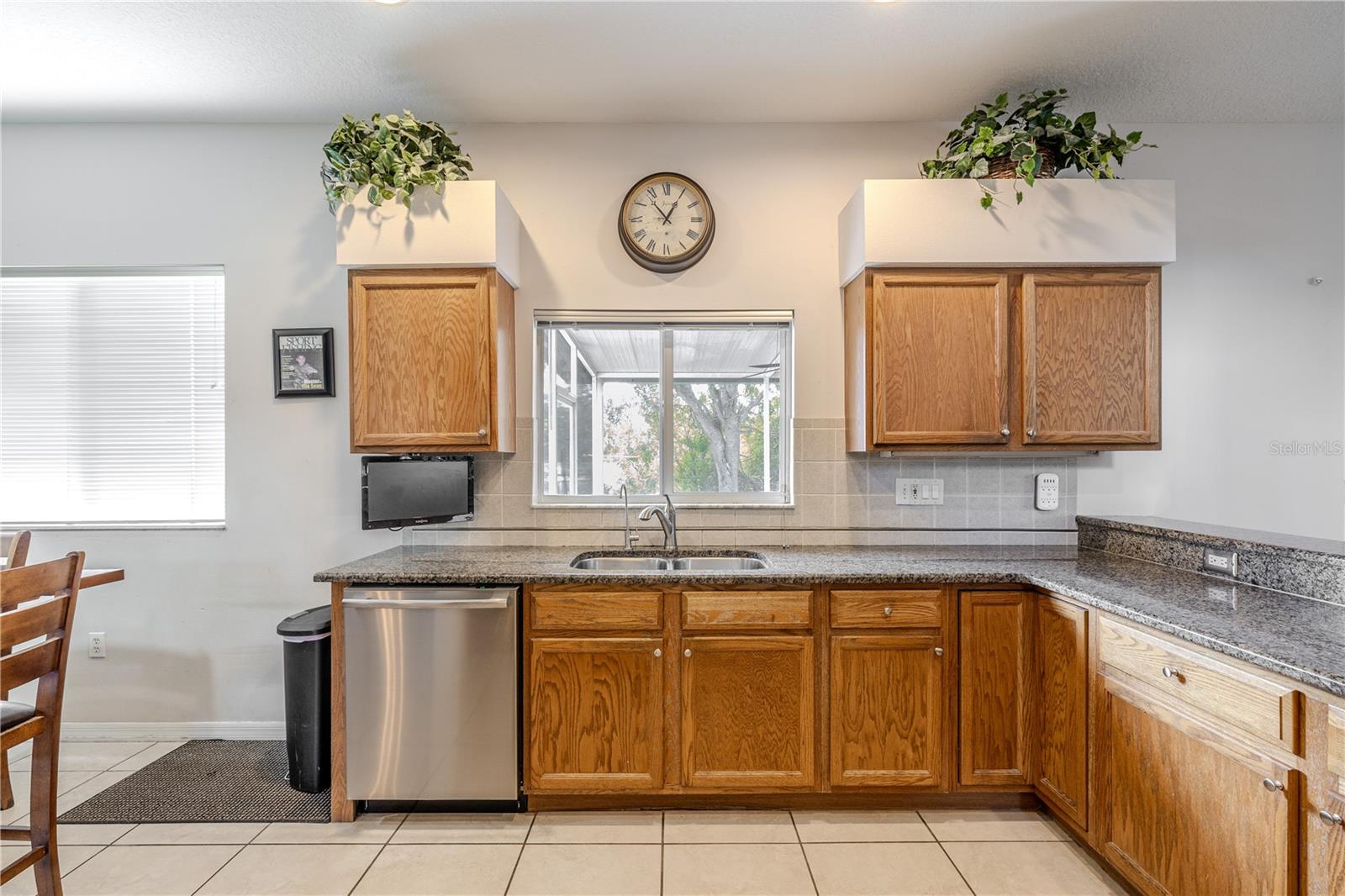 Kitchen offers generous granite counter space, a convenient breakfast bar, and a window over the sink that brings in natural light and views to the lanai and backyard.