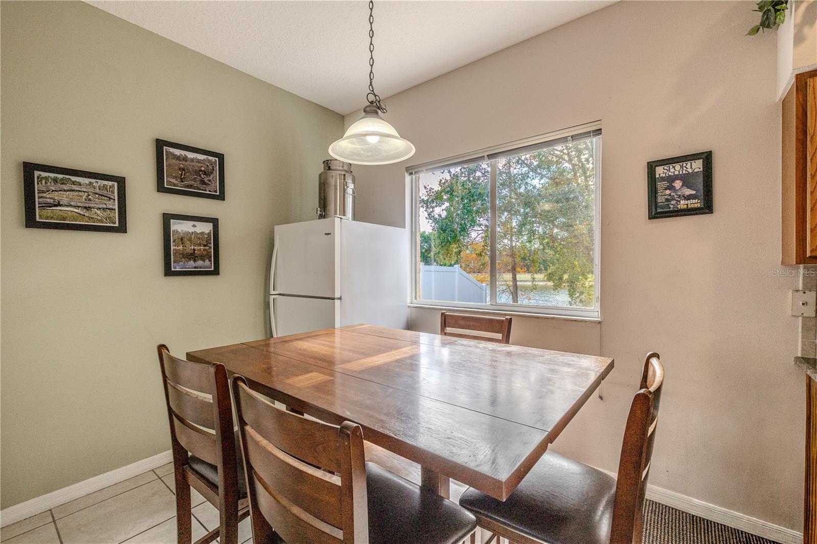 Sunny breakfast nook features pendant lighting and a large picture window with peaceful pond and tree views—perfect for casual meals and morning coffee.