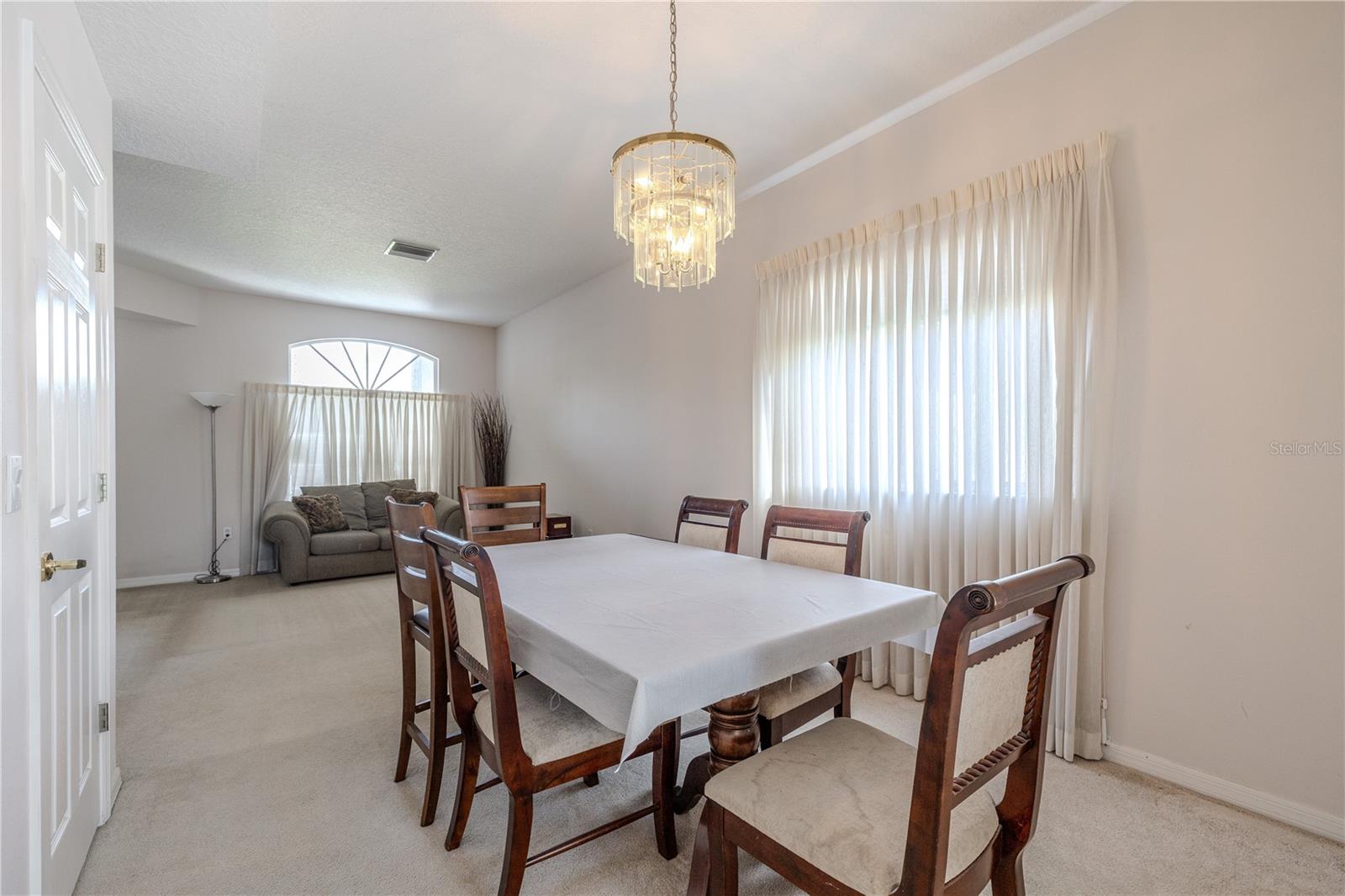 Elegant formal dining room is filled with natural light and features a statement chandelier, creating the perfect space for hosting dinners and special occasions.