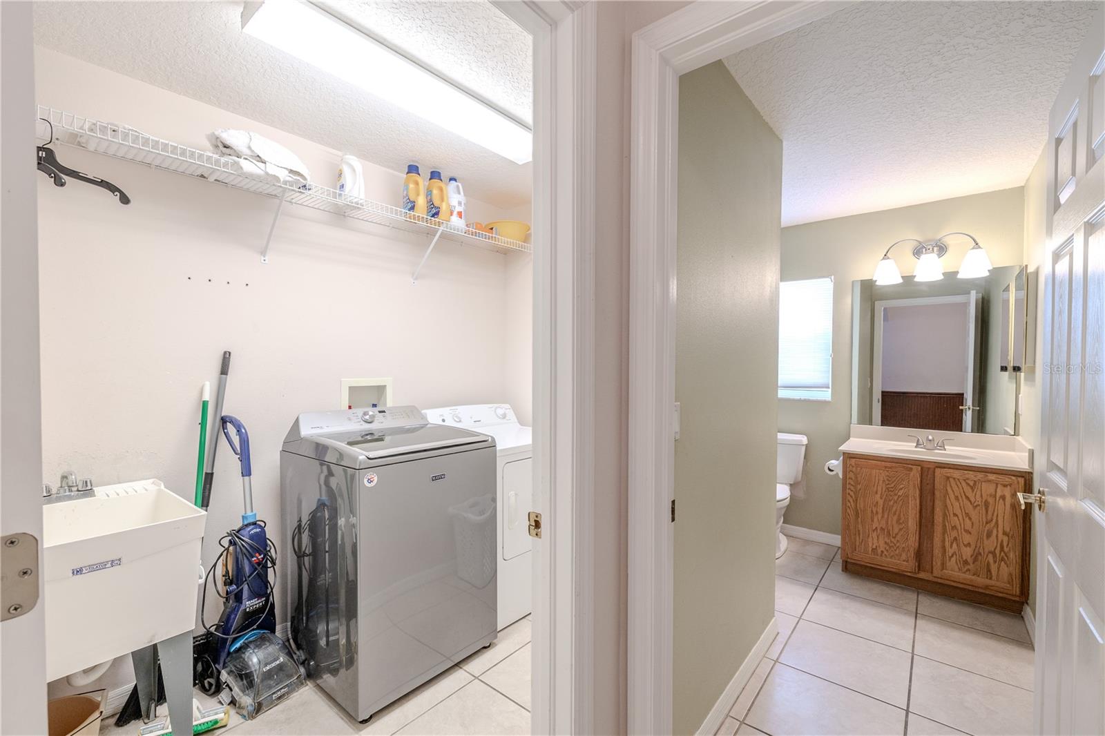 Conveniently located just off the garage entry, this hallway offers a dedicated laundry room and easy access to the second full bathroom.