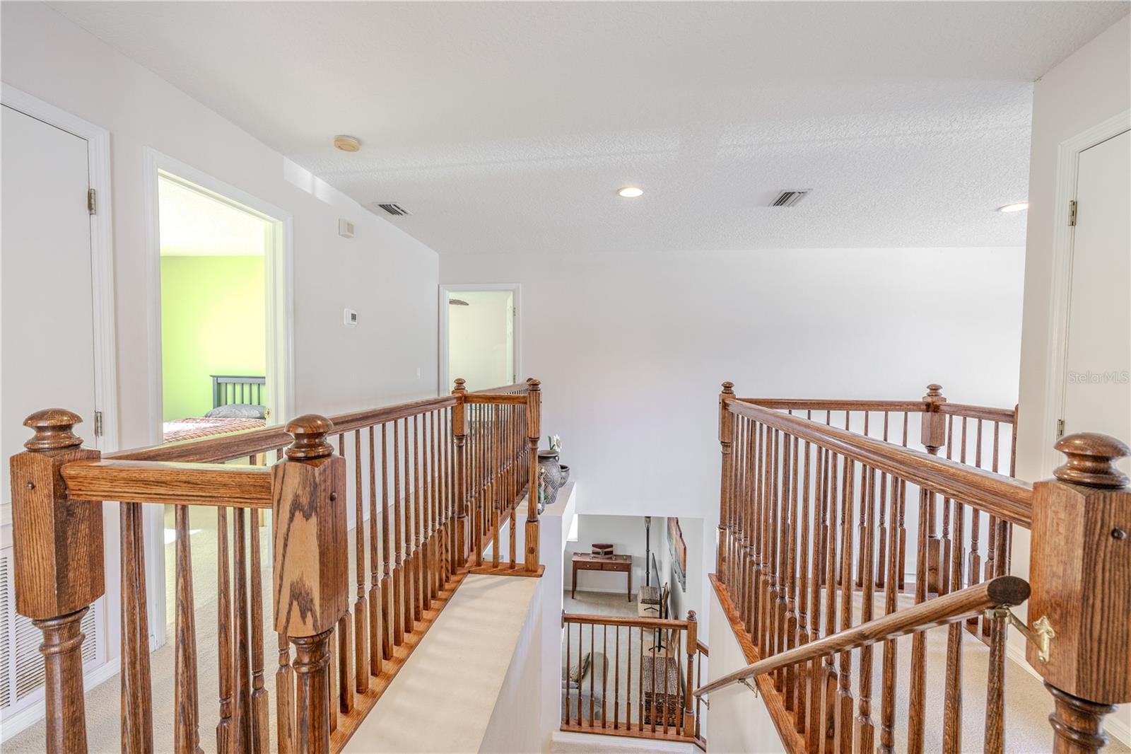 Spacious upstairs loft/landing features warm wood railings and overlooks the two-story foyer, creating a bright, open feel with easy access to the bedrooms.