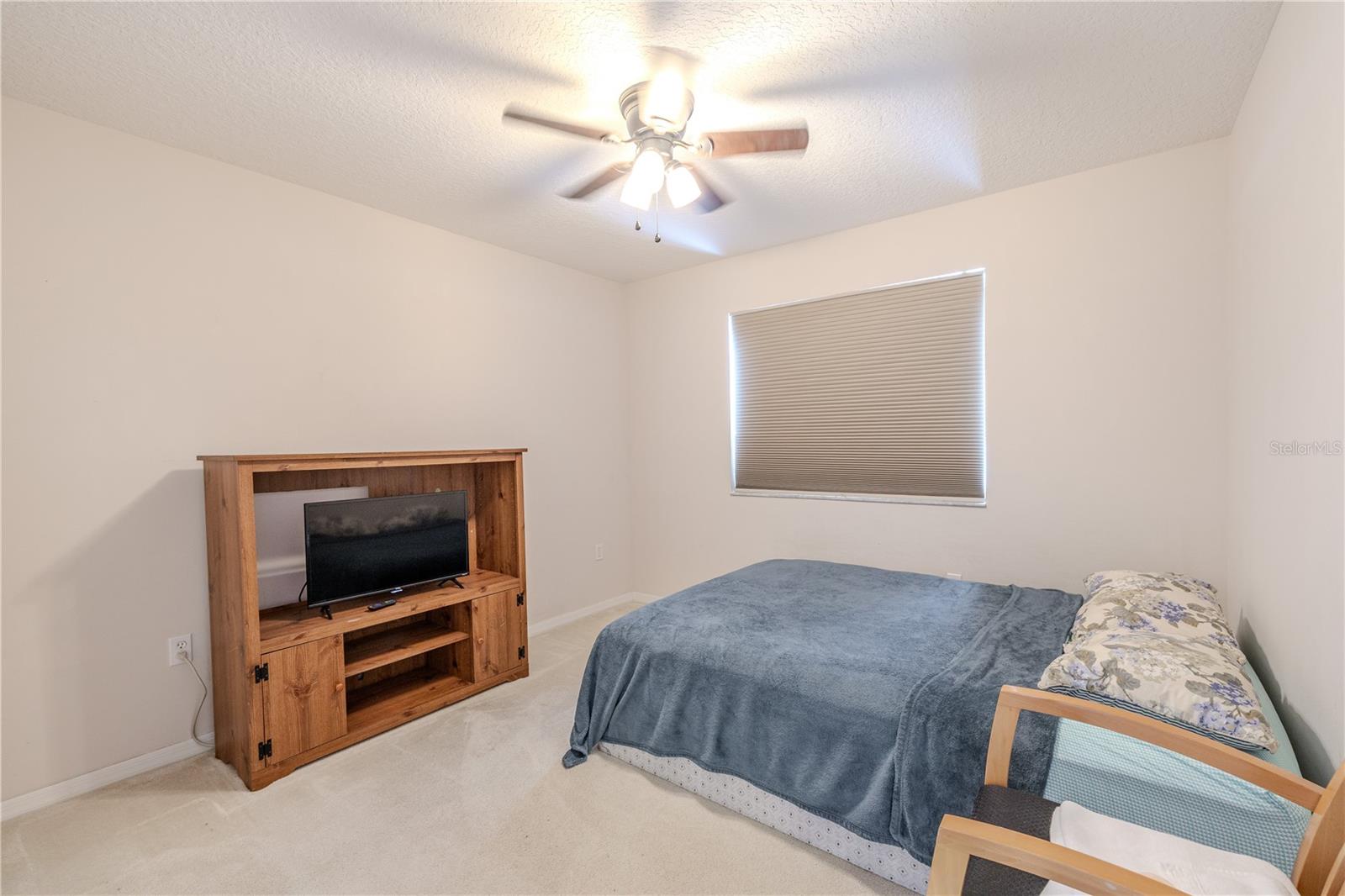 Comfortable third bedroom features plush carpeting, a ceiling fan with light, and a spacious layout ideal for guests, kids, or a home office.
