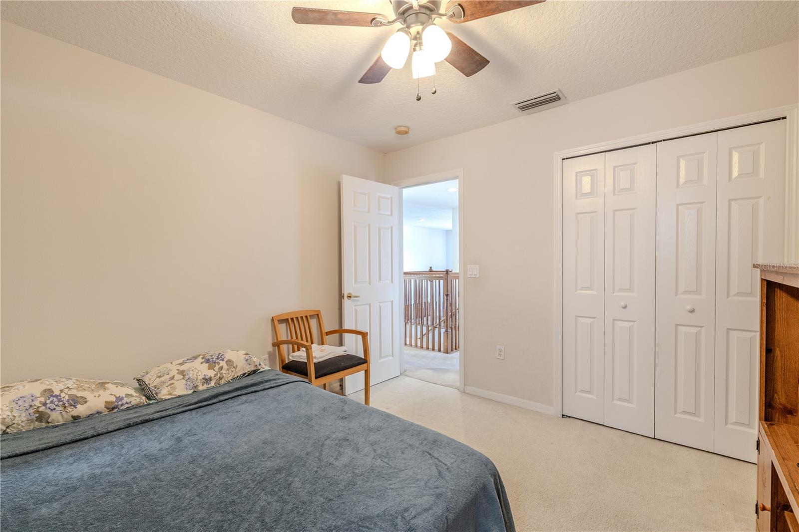 Third bedroom offers plush carpeting, a ceiling fan with light, and a generous double-door closet, providing comfortable space for guests or a home office.