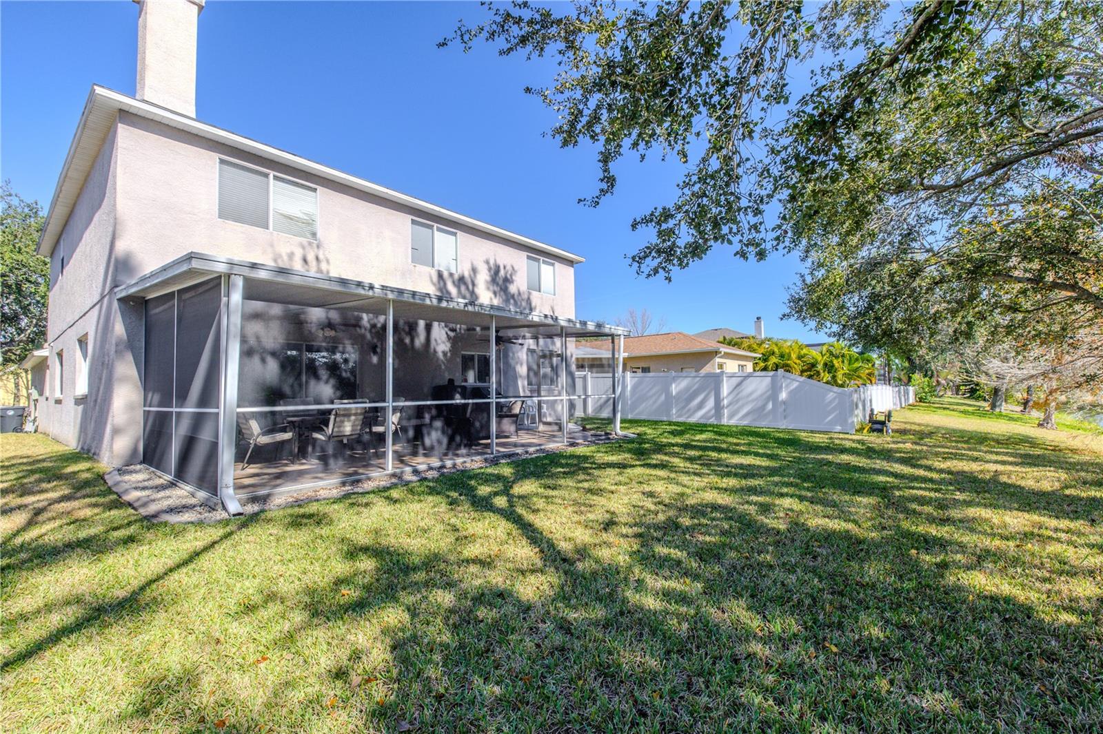 Spacious backyard offers a large, fully fenced lawn with mature shade trees and a generous screened lanai, creating the perfect setting for relaxing and entertaining.
