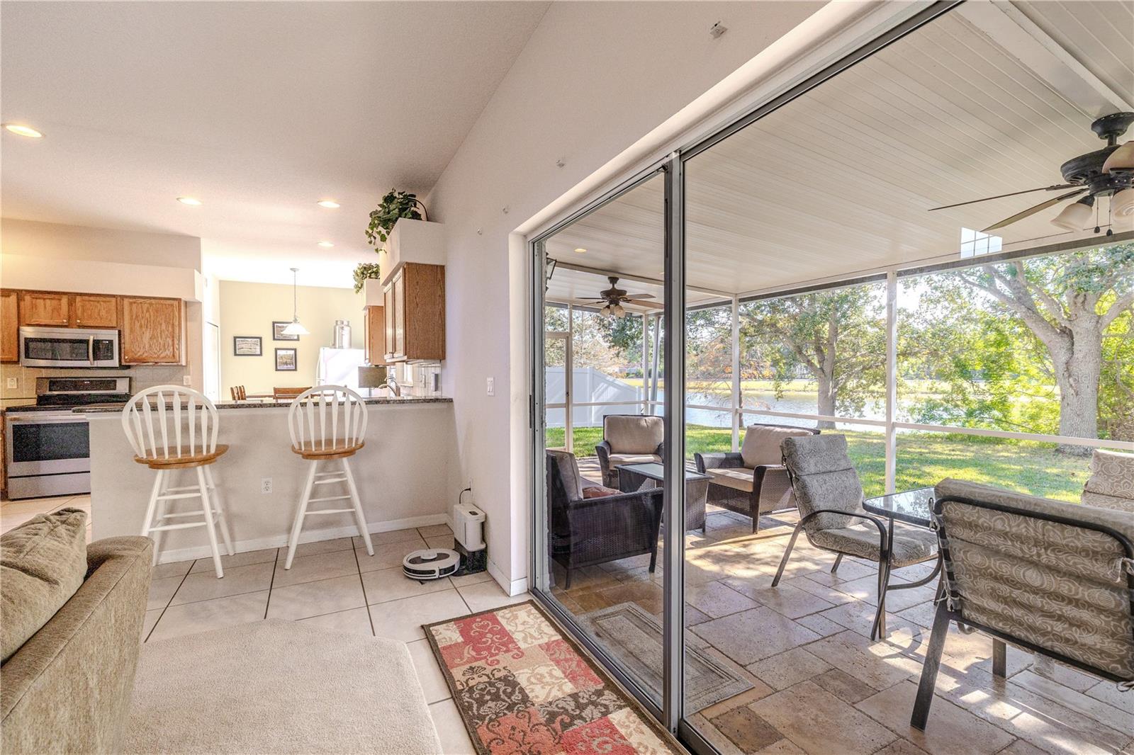 Expansive sliding glass doors connect the kitchen and living area to a relaxing screened lanai with seating and peaceful water views—ideal for true Florida indoor-outdoor living.