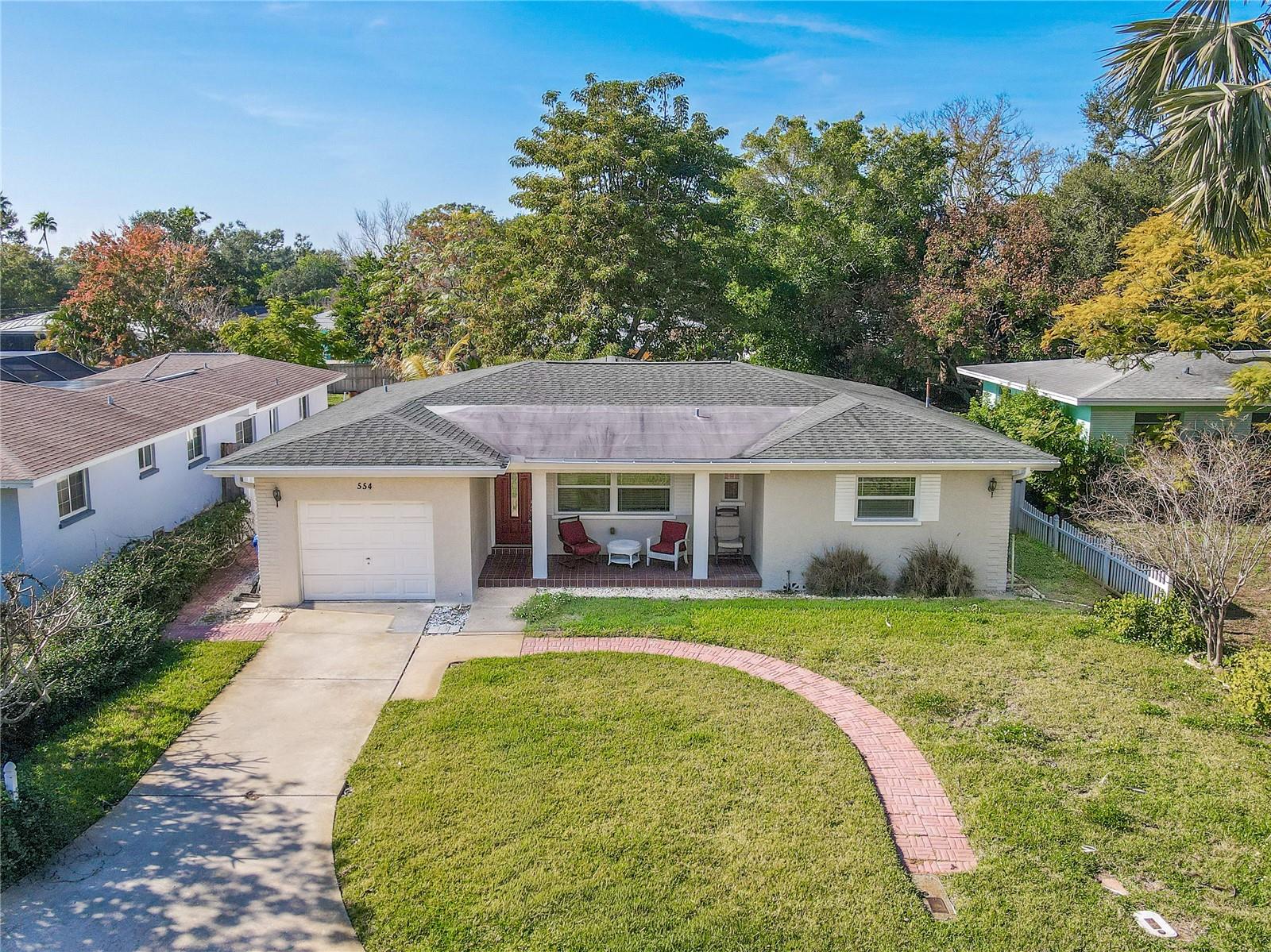 Charming single-story home with a one-car garage, covered front porch, spacious front yard, vinyl fenced back yard, and a welcoming setting framed by mature trees for added privacy.