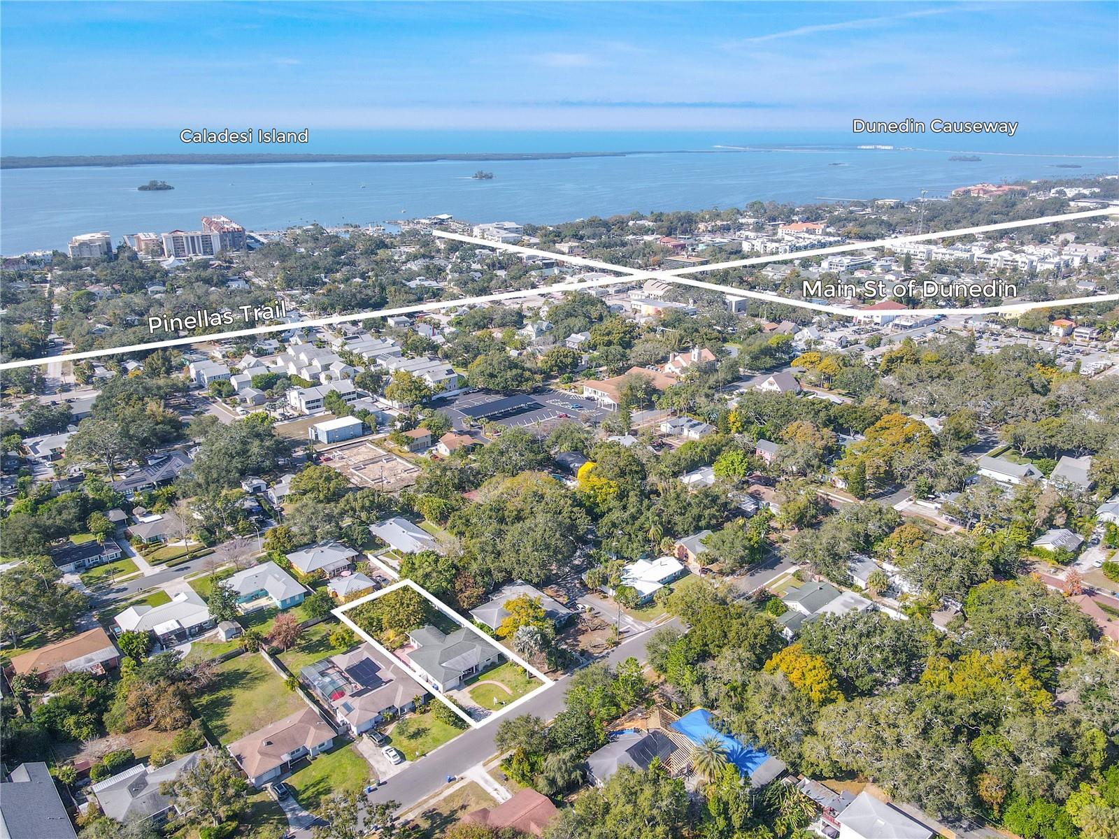 Aerial location view highlighting the home’s outlined lot just minutes from the Pinellas Trail, downtown Dunedin’s Main Street, the Dunedin Causeway, and Caladesi Island.