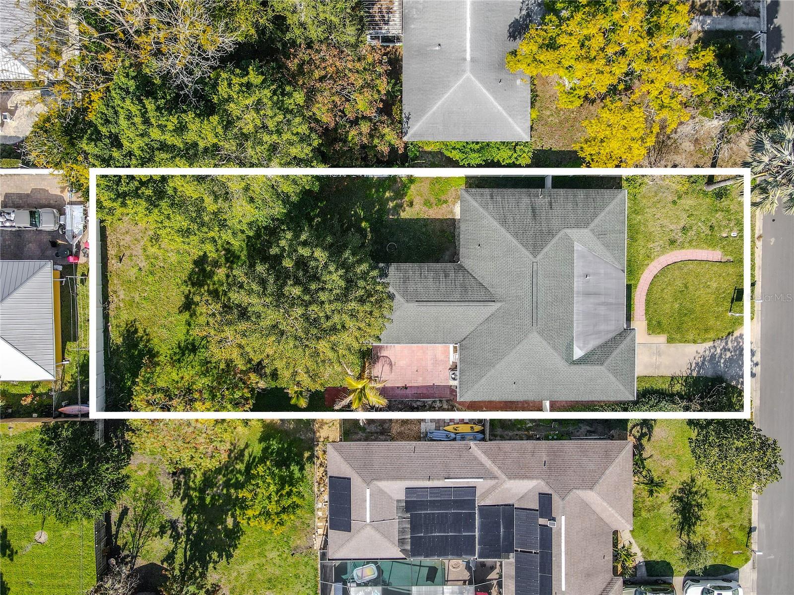 Overhead aerial view outlining the full property, showcasing the home’s footprint, driveway and front walkway, and a deep backyard shaded by mature trees for added privacy.