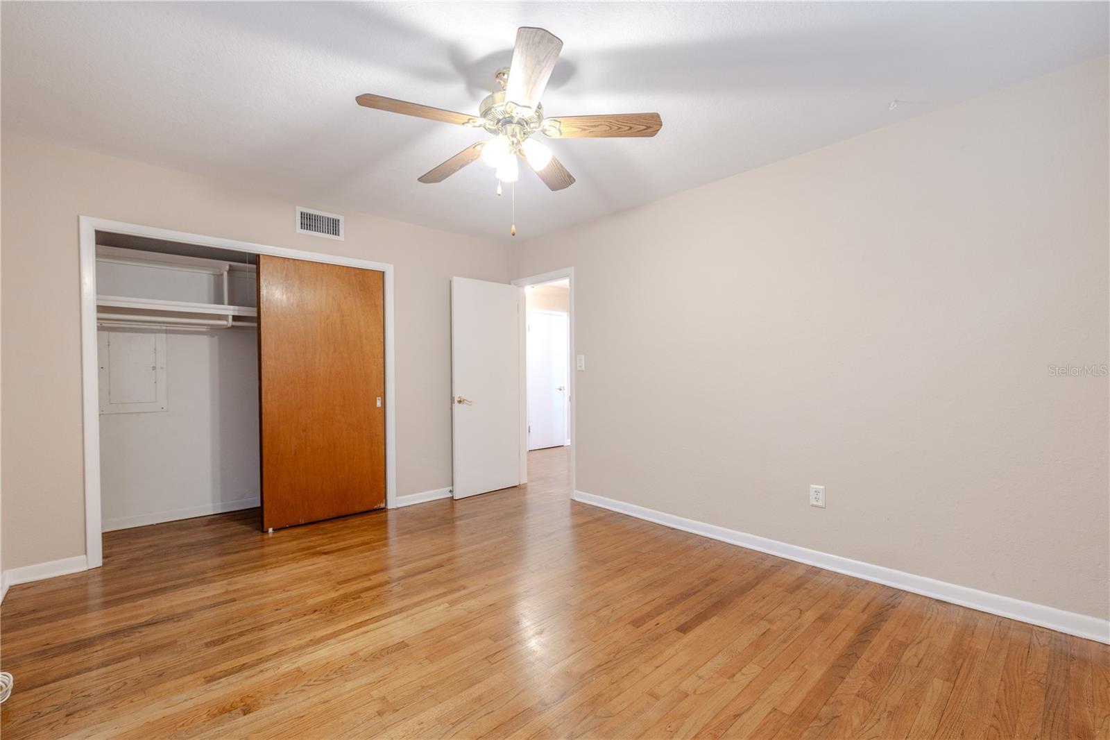 Spacious second bedroom with hardwood floors, ceiling fan, and a large closet, offering a bright, comfortable space for guests or everyday living.