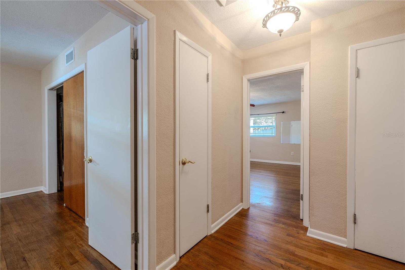 Hallway view highlighting the second and primary bedroom with hardwood floors, multiple storage/linen closets, and easy access to the bedrooms and full bath.