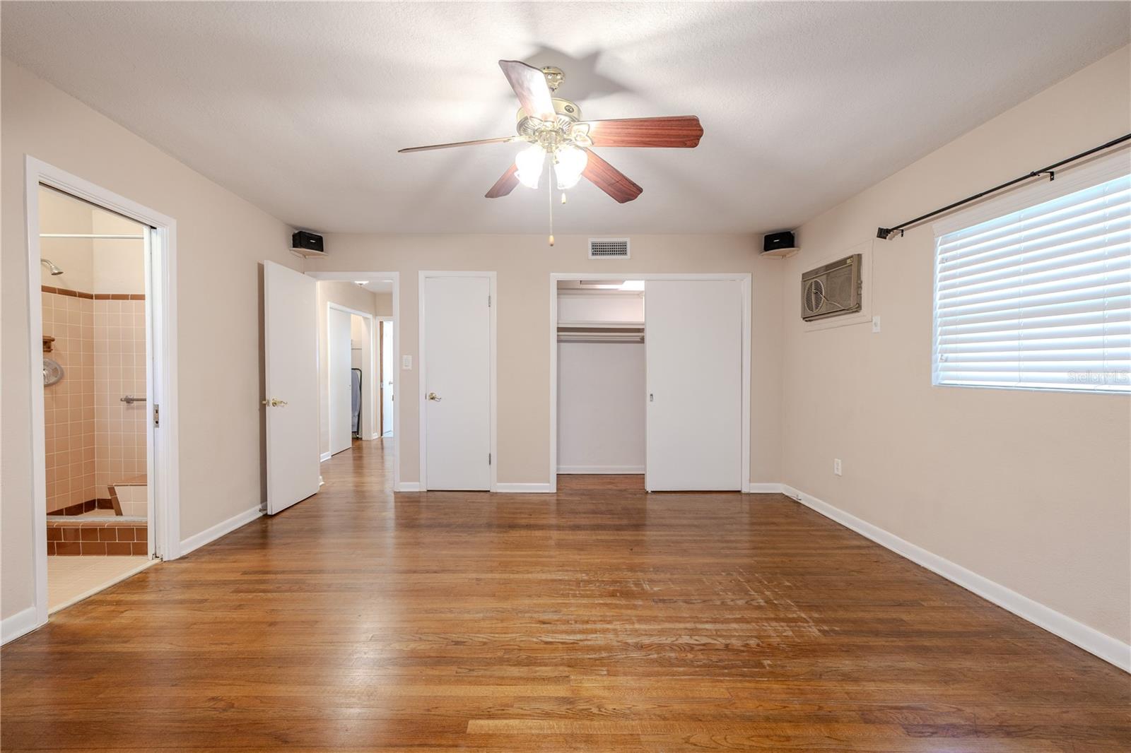 Additional view of the spacious primary bedroom, en-suite bathroom, with hardwood floors, ceiling fan, and dual windows that bring in abundant natural light for a bright, comfortable retreat.