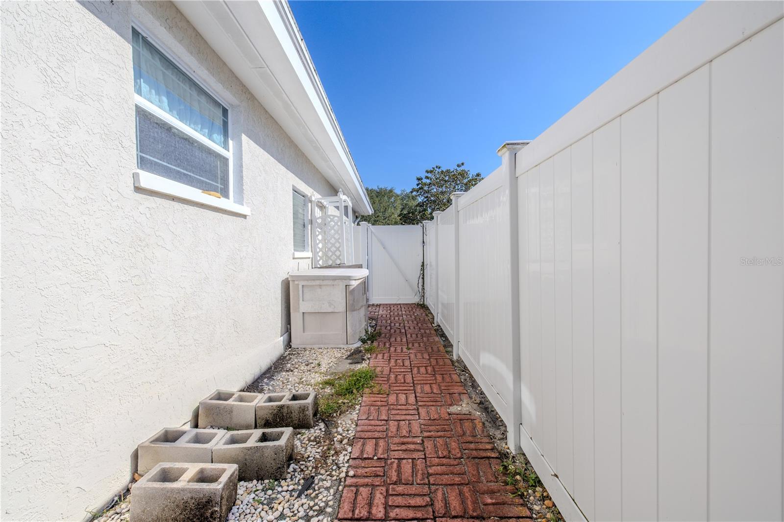 Fenced side yard with a brick walkway and gate access—ideal for added privacy, and storage.