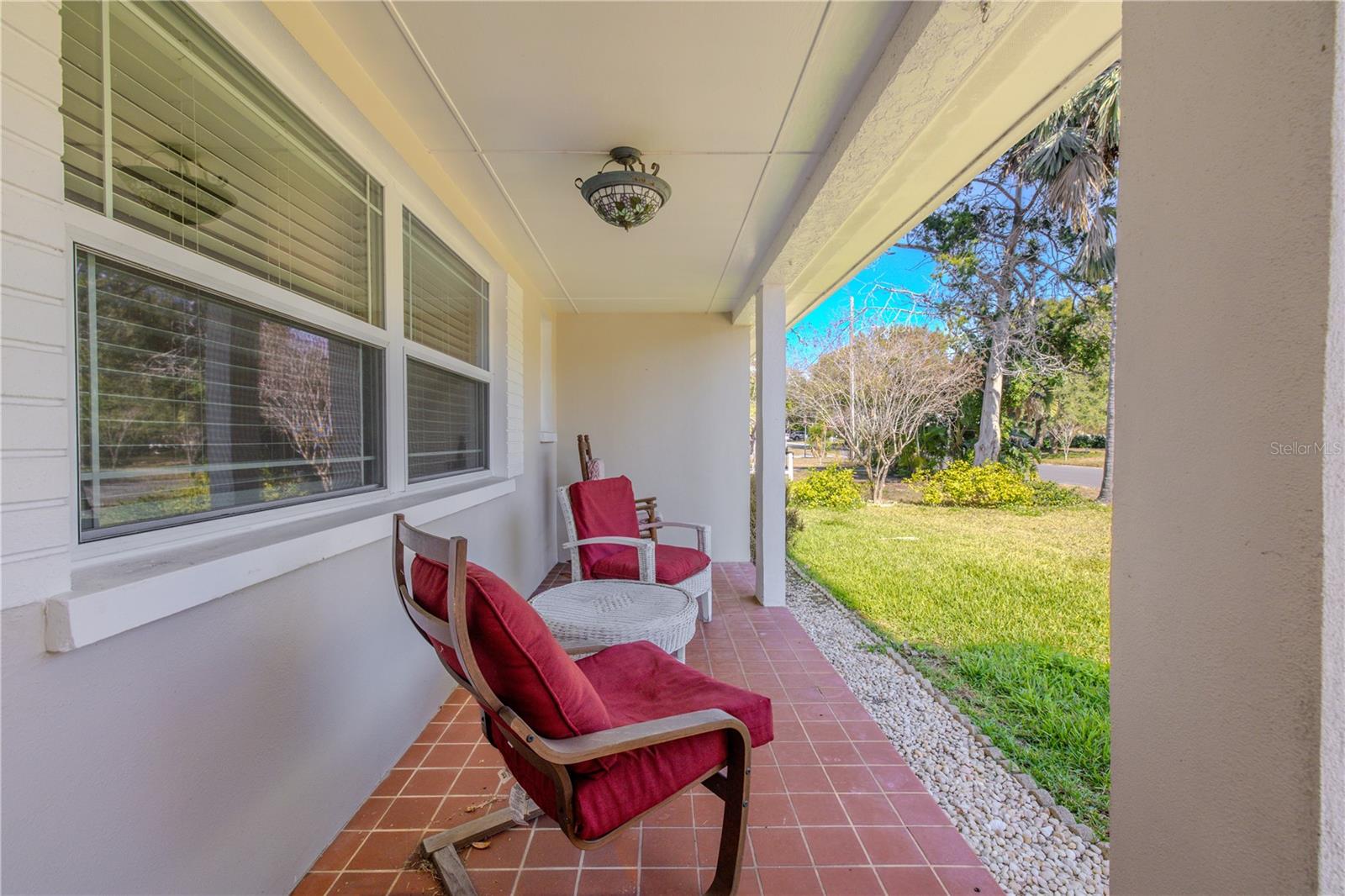 Additional view of the inviting covered front porch with classic tile flooring, seating space for relaxing, and a striking red front door that adds charming curb appeal.