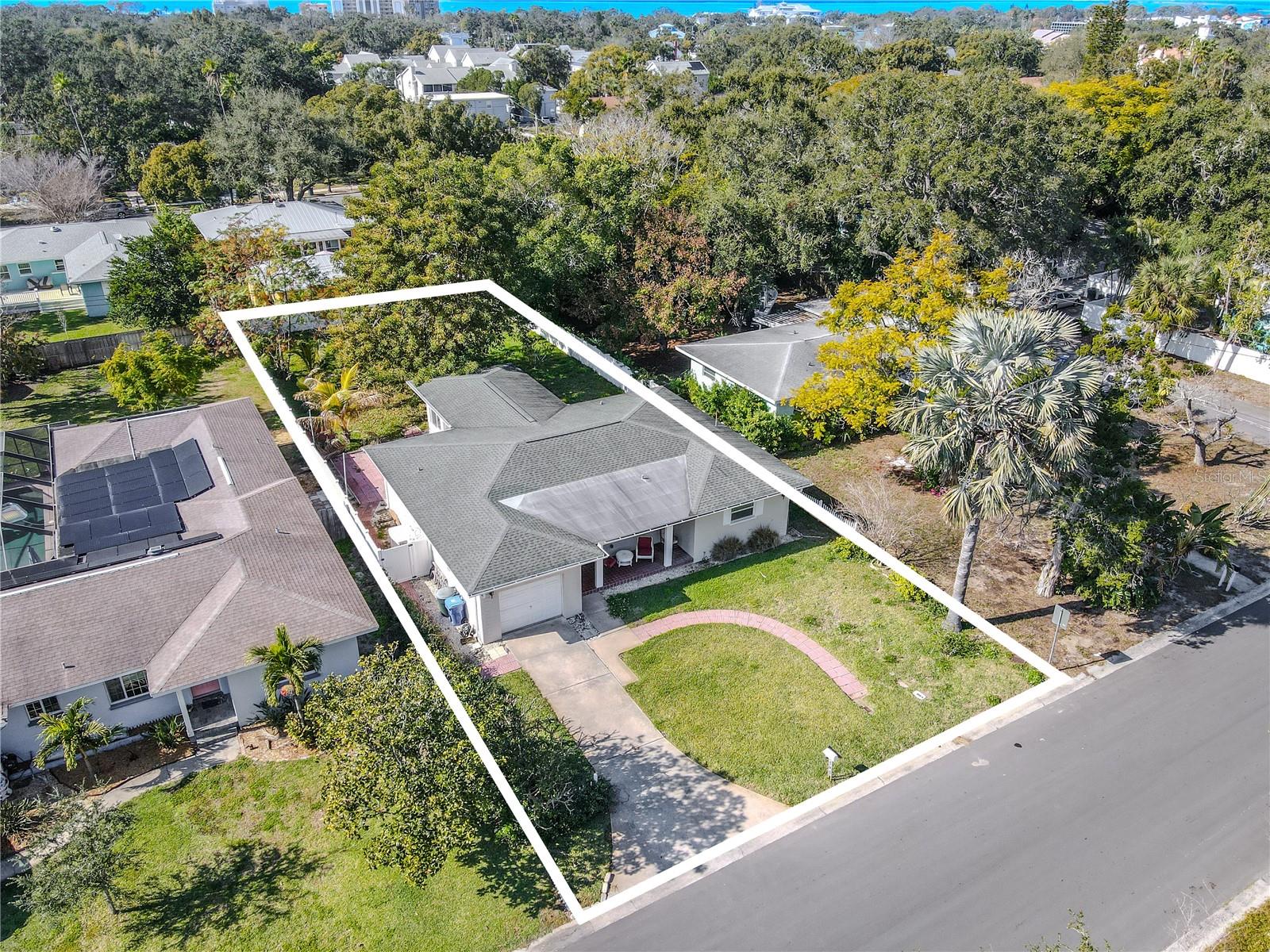 Additional side overhead aerial view outlining the full property, showcasing the home’s footprint, driveway and front walkway, and a deep backyard shaded by mature trees for added privacy.
