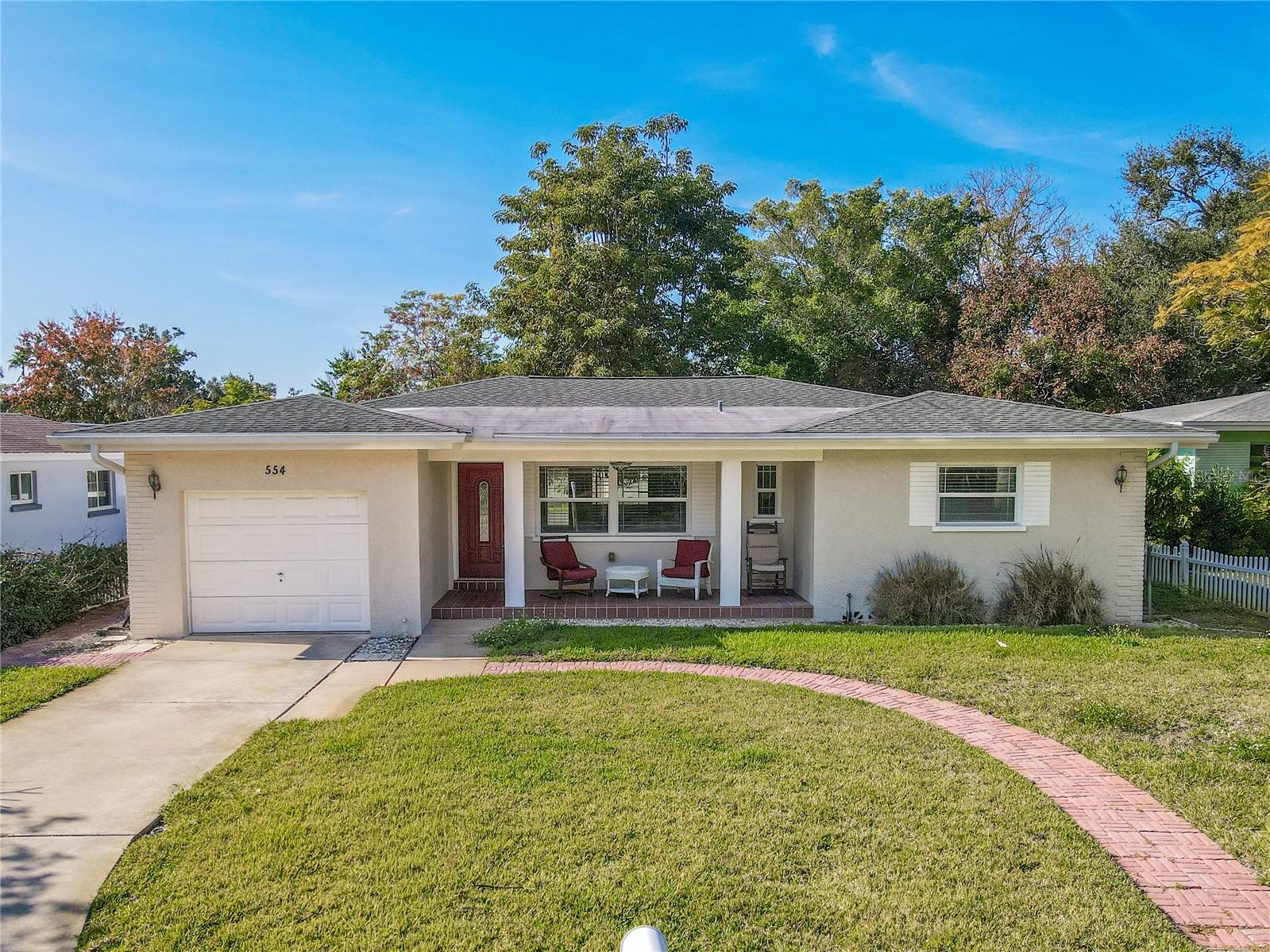Charming single-story home with a one-car garage, covered front porch, spacious front yard, vinyl fenced back yard, and a welcoming setting framed by mature trees for added privacy.