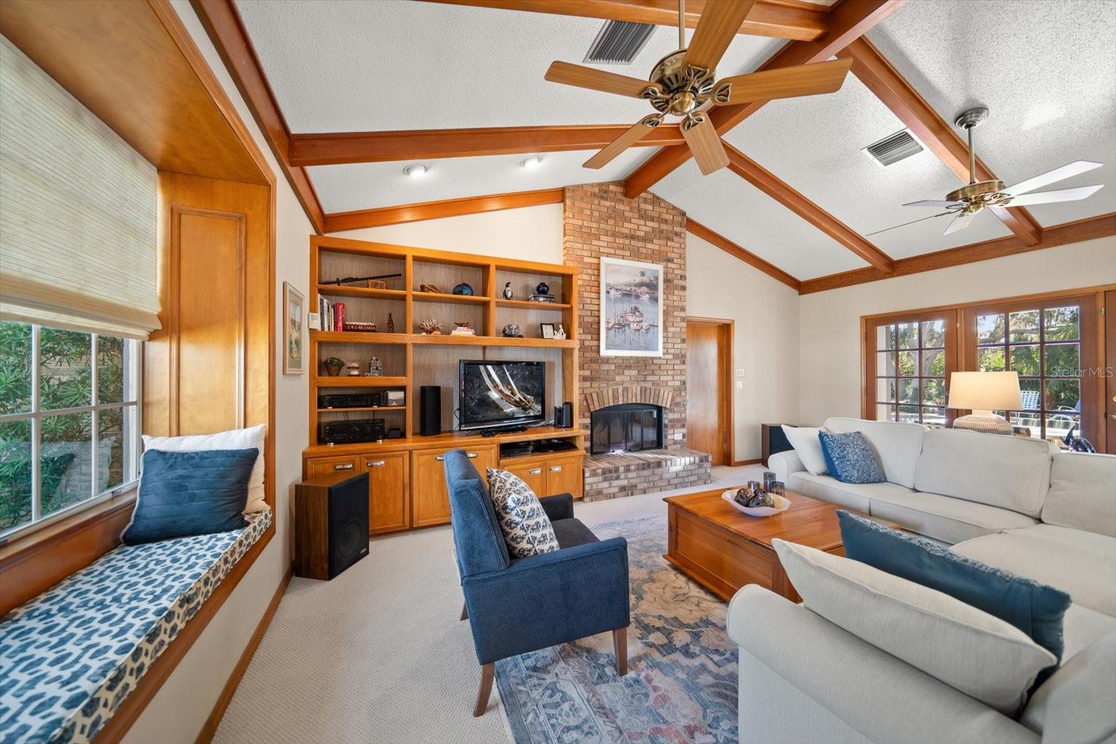Family room detailed by custom wood planked vaulted ceilings, integrated storage and French doors.
